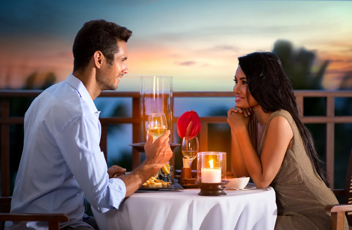 Un couple heureux lors d'une soirée d'été en train de prendre un dîner romantique en plein air | Source : Shutterstock