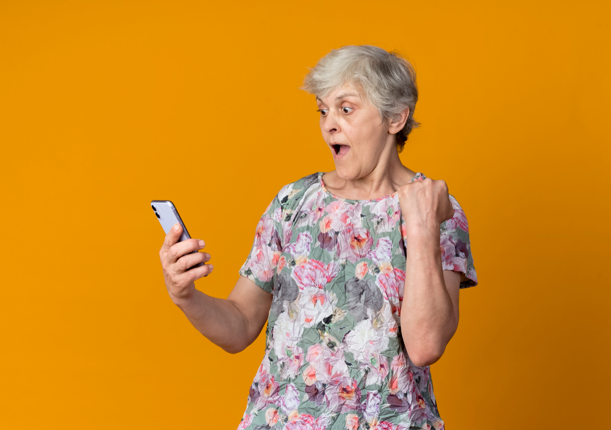 Une femme âgée réagissant en état de choc en regardant son téléphone | Source : Freepik