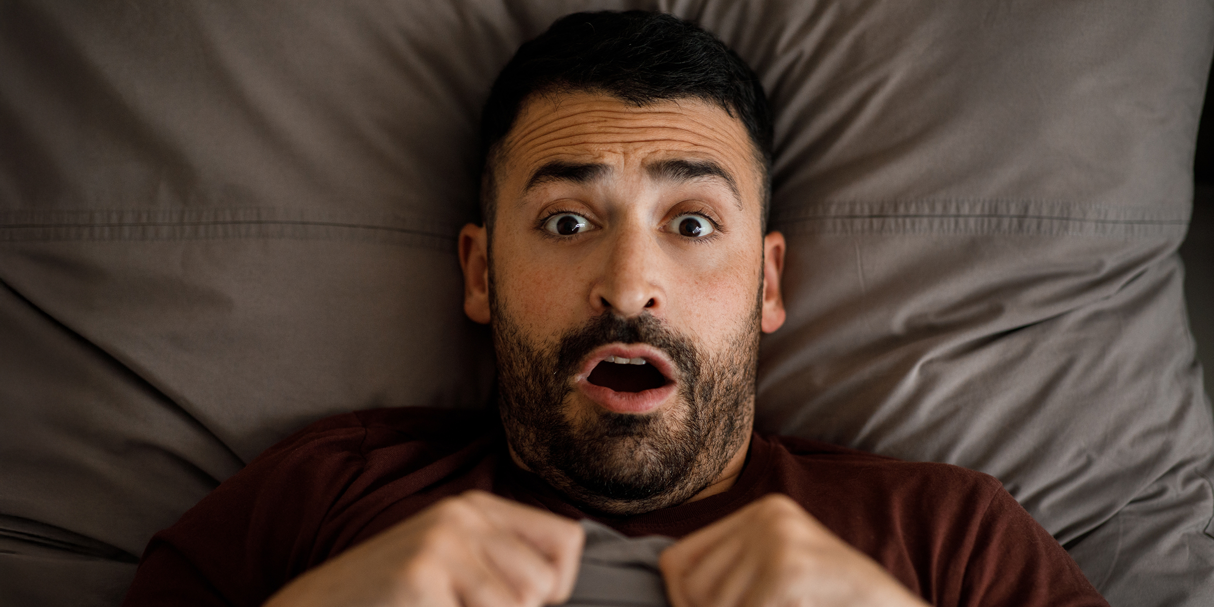 Un homme choqué dans son lit | Source : Shutterstock