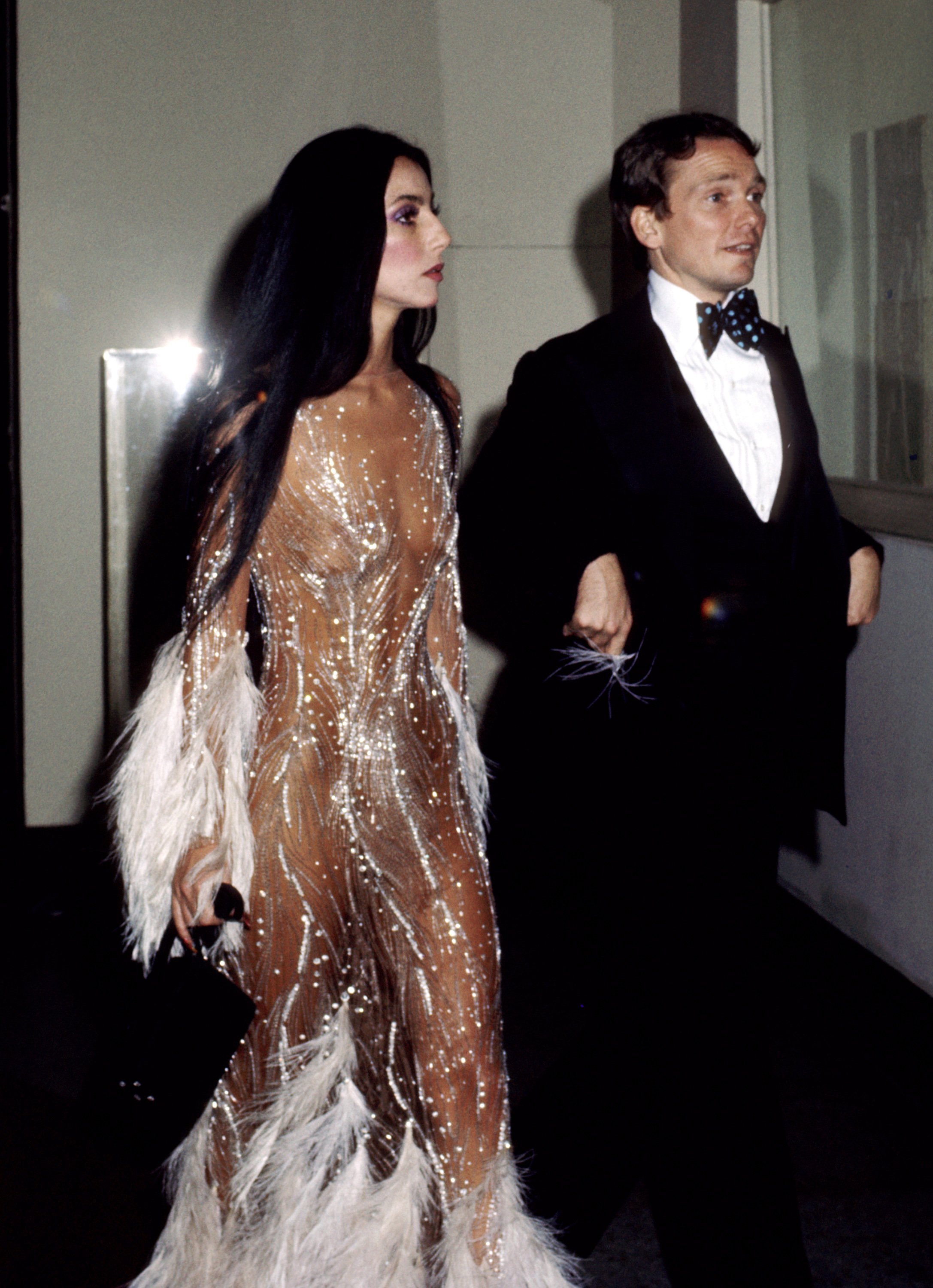 Cher vêtue de la robe illusion nude de Bob Mackie, escortée par Bob Mackie au Met Gala en 1974 | Source : Getty Images