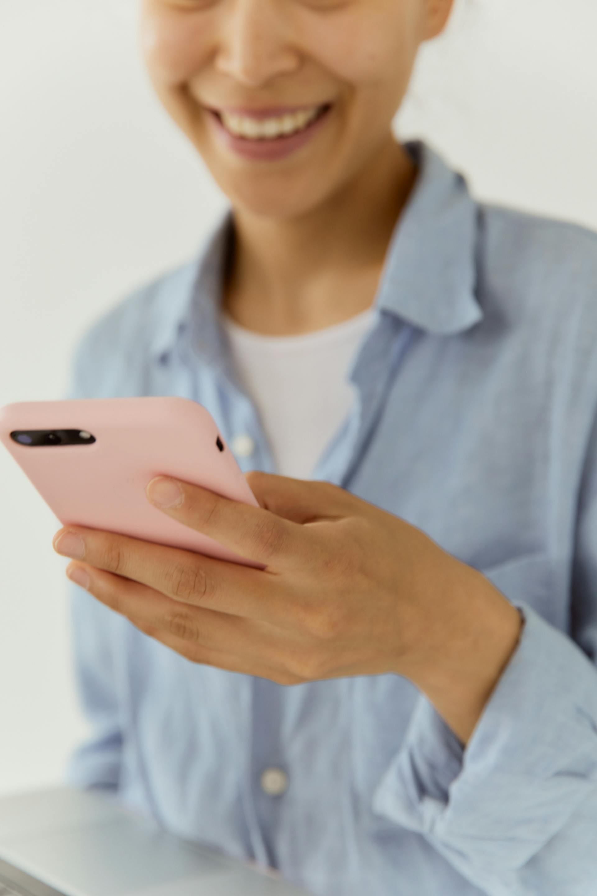 Une femme qui sourit en regardant son téléphone | Source : Pexels