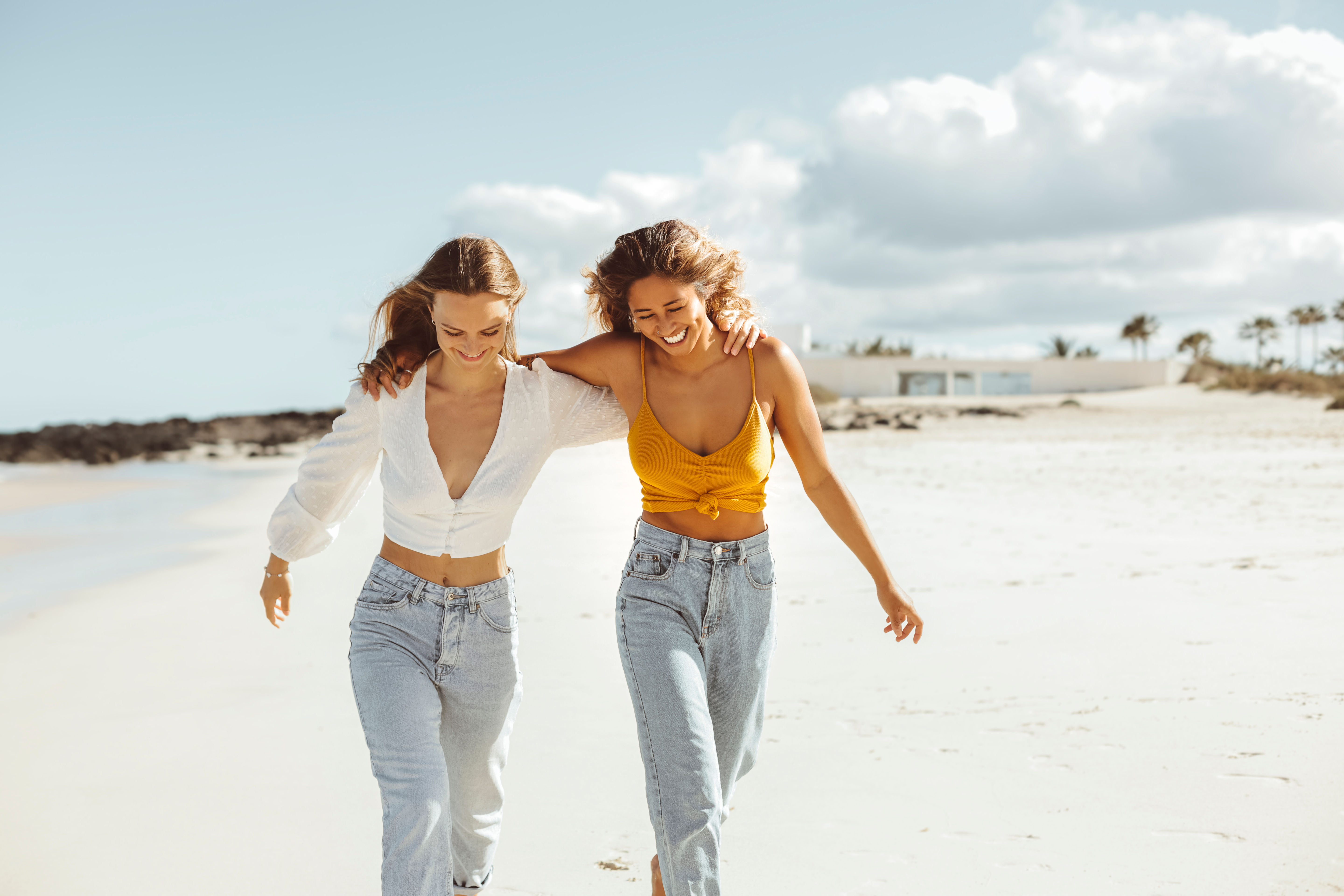 Deux meilleurs amis marchant le long d'une plage et riant | Source : Shutterstock