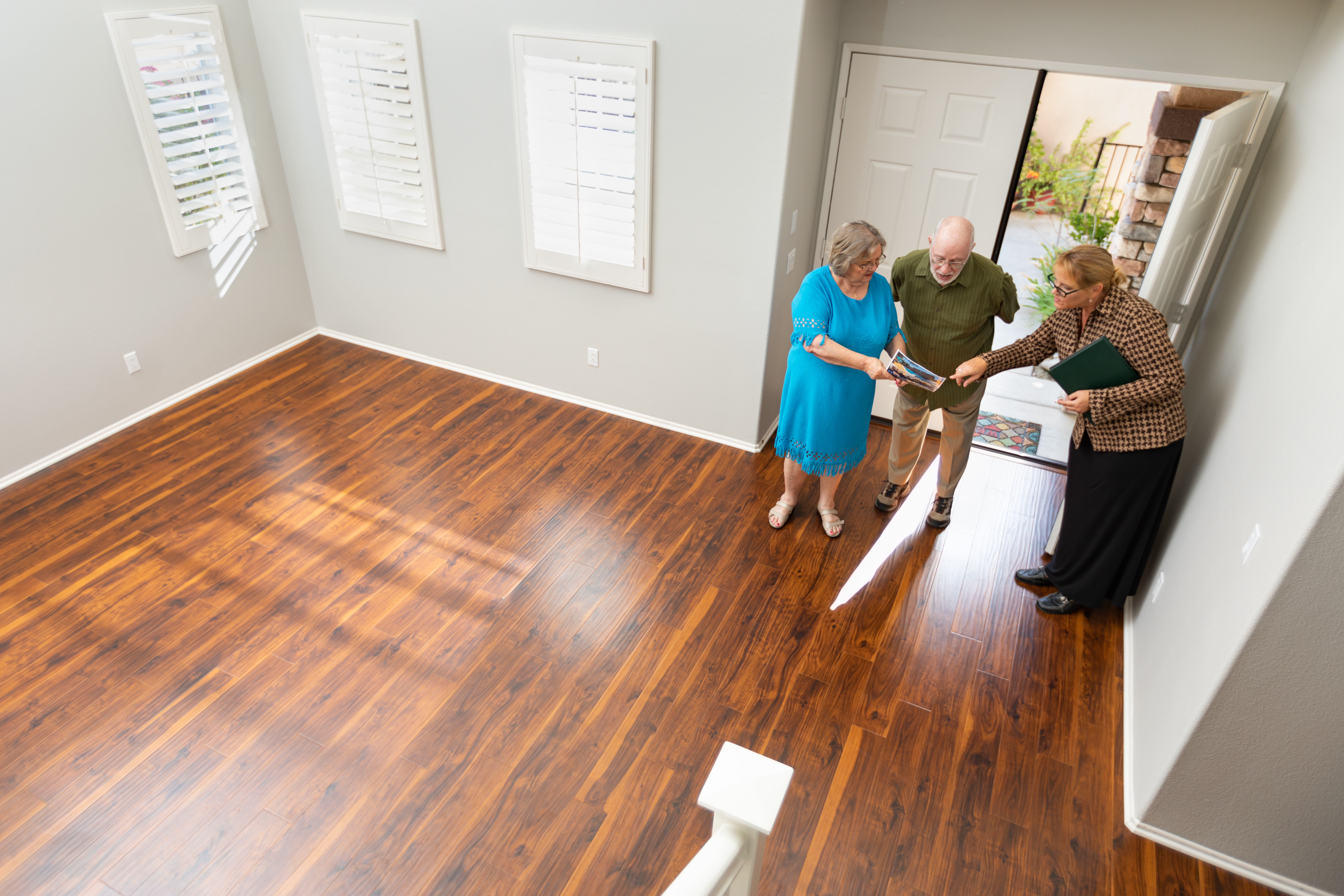Trois personnes discutant d'une maison près de la porte d'une pièce vide | Source : Shutterstock