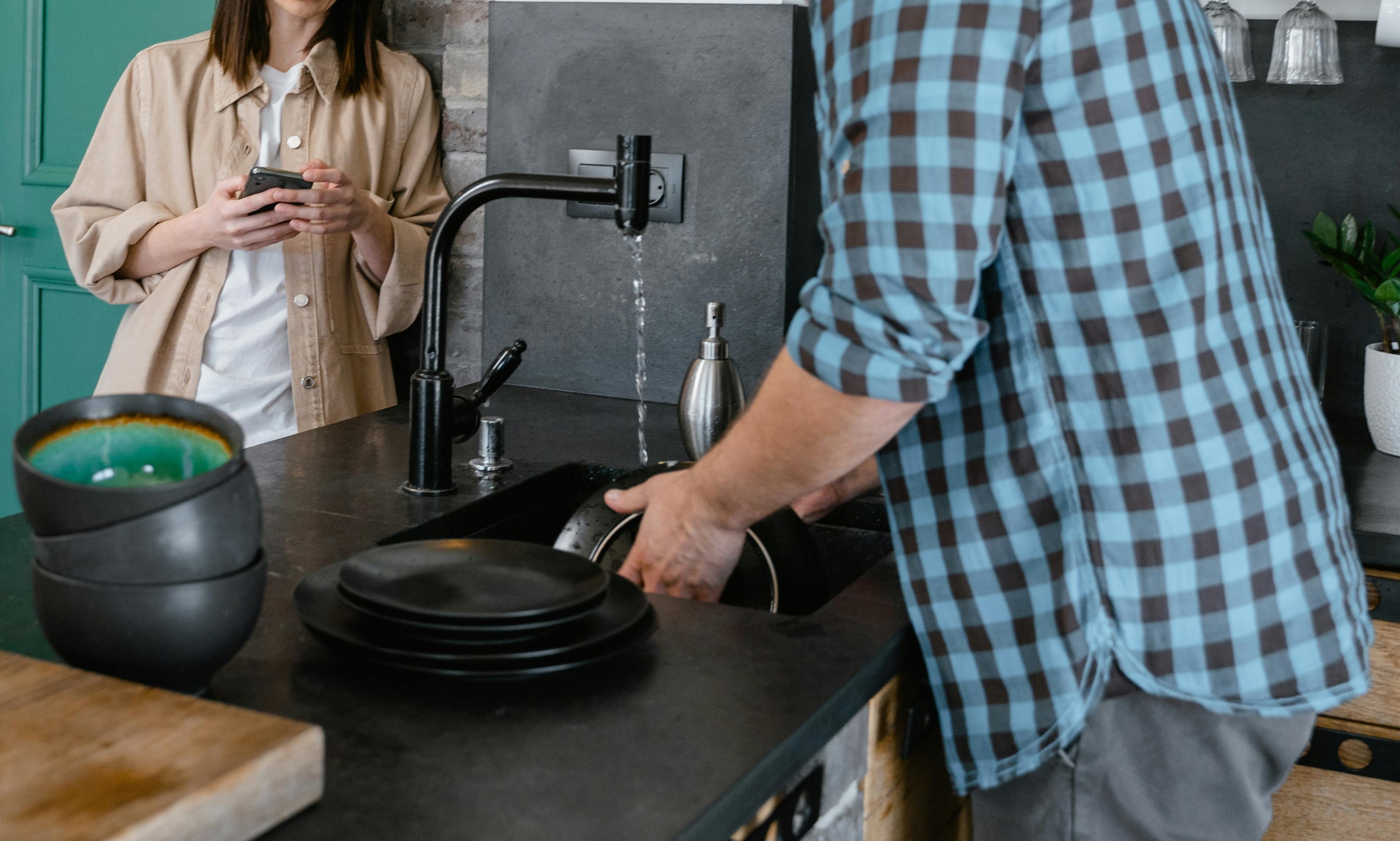 Une femme observant un homme en train de faire la vaisselle dans la cuisine | Source : Pexels