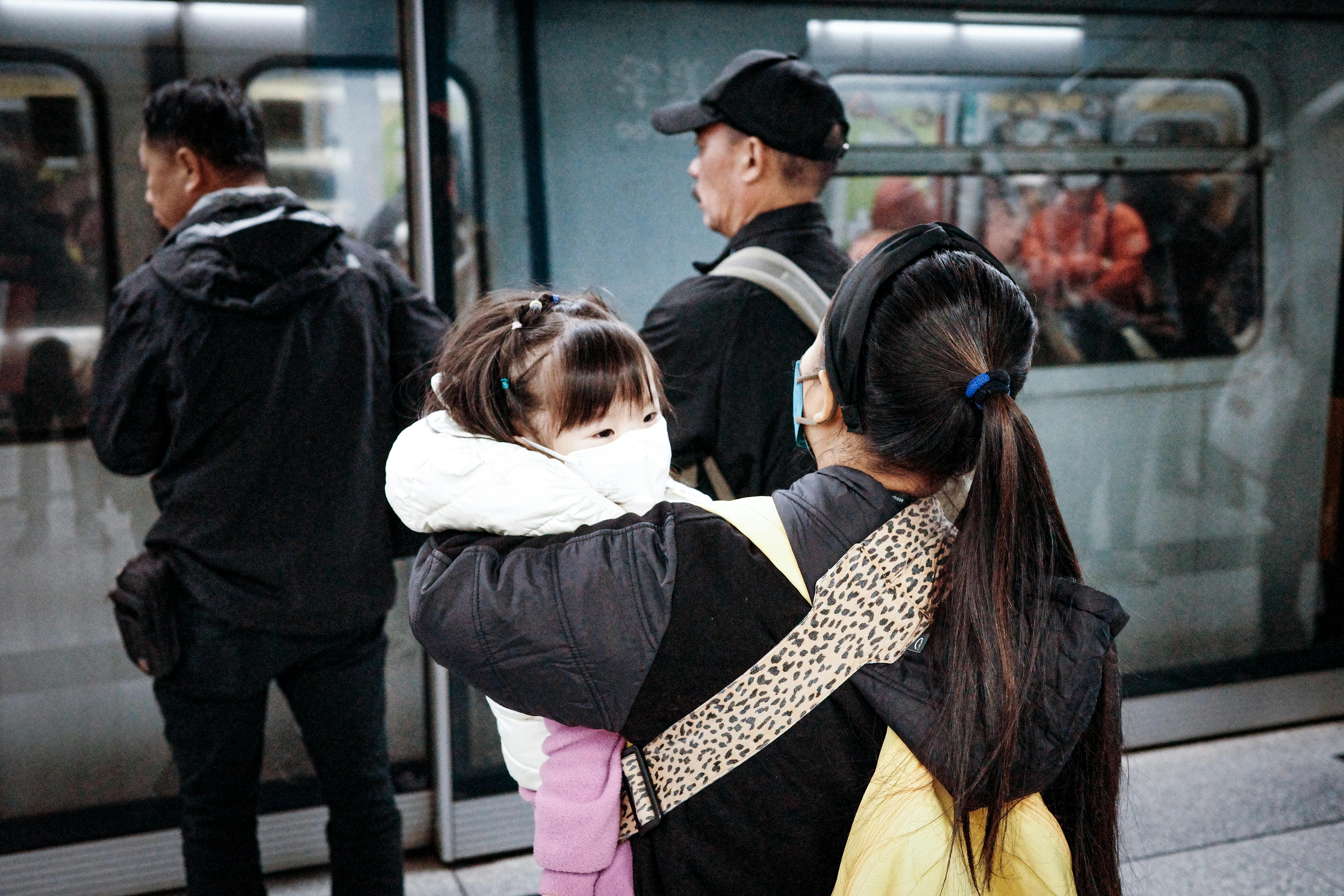 Une femme tenant un enfant s'apprête à monter dans le métro | Source : Pexels