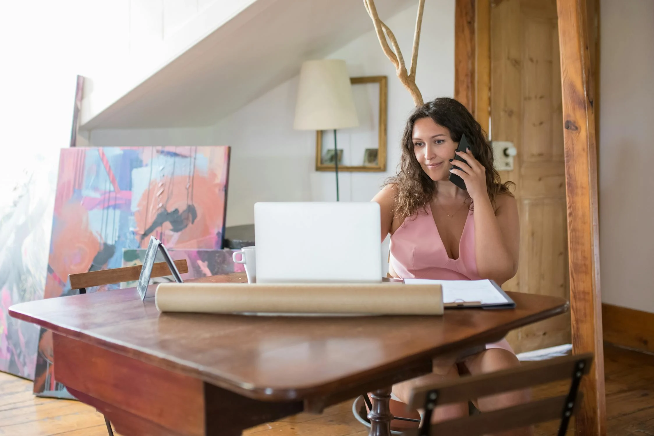 Une femme qui parle sur son téléphone et regarde son ordinateur portable | Source : Pexels