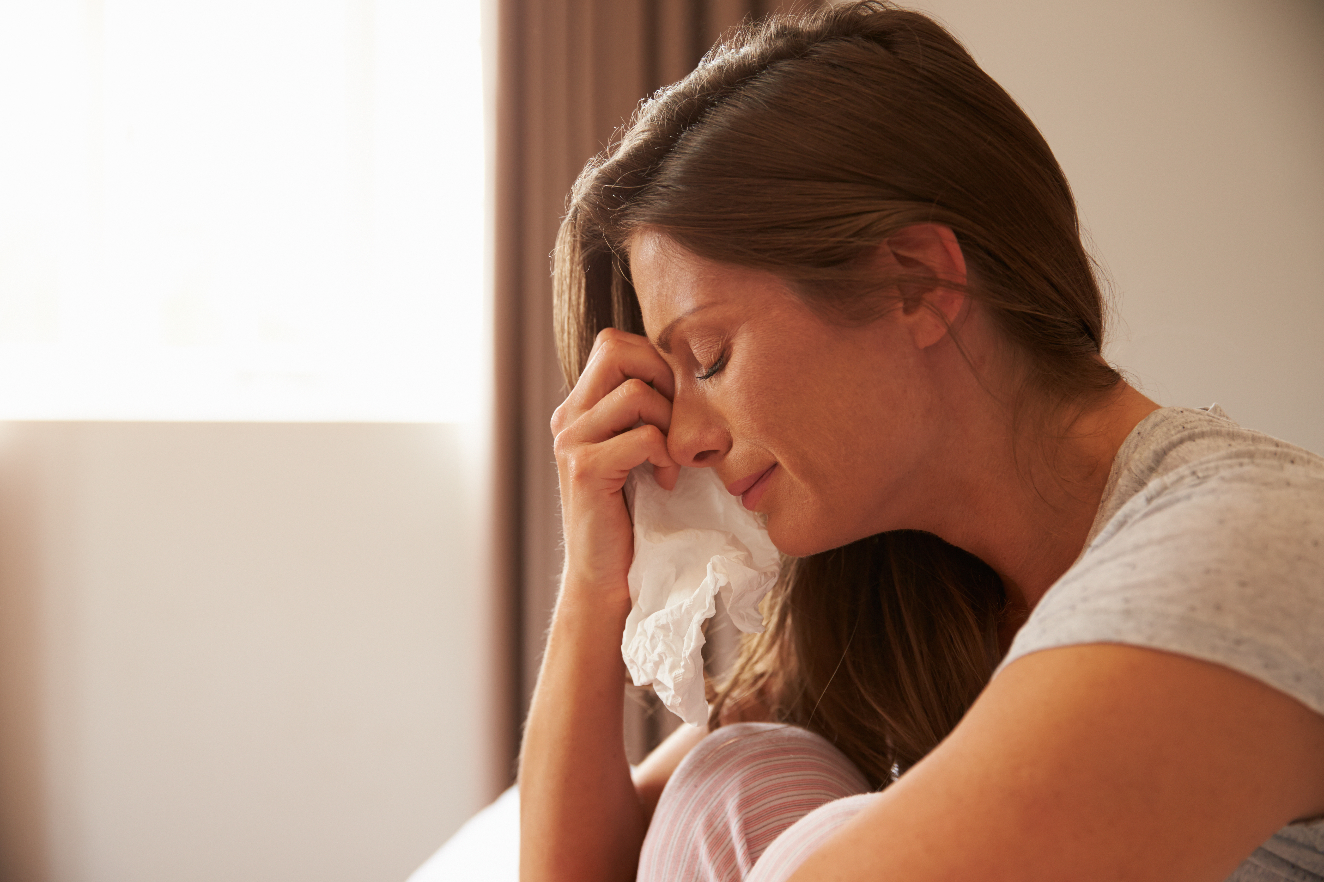Une femme qui pleure en essuyant ses larmes avec un mouchoir en papier | Source : Shutterstock