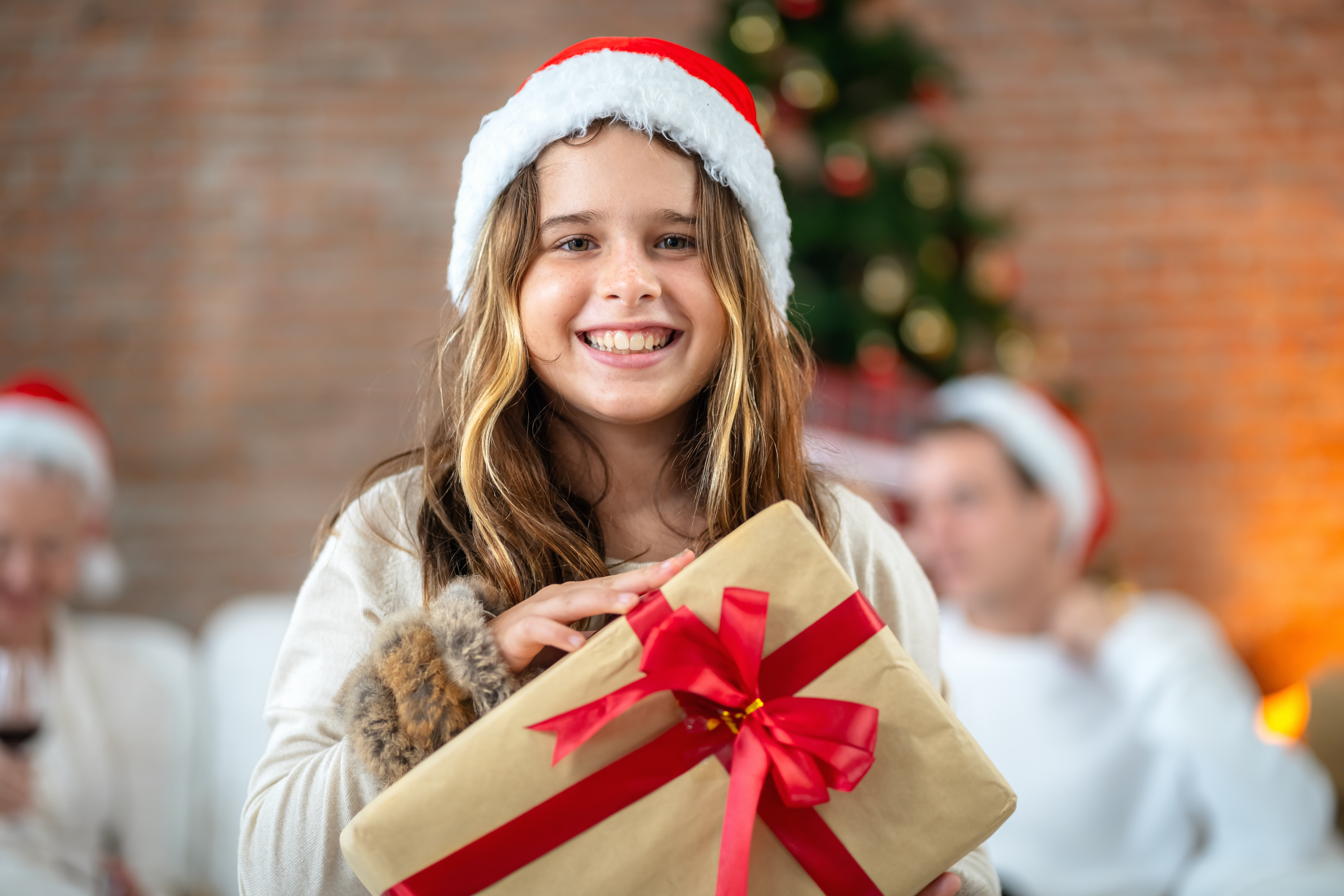 Une jeune fille tenant un paquet cadeau sourit joyeusement le jour de Noël. | Source : Getty Images