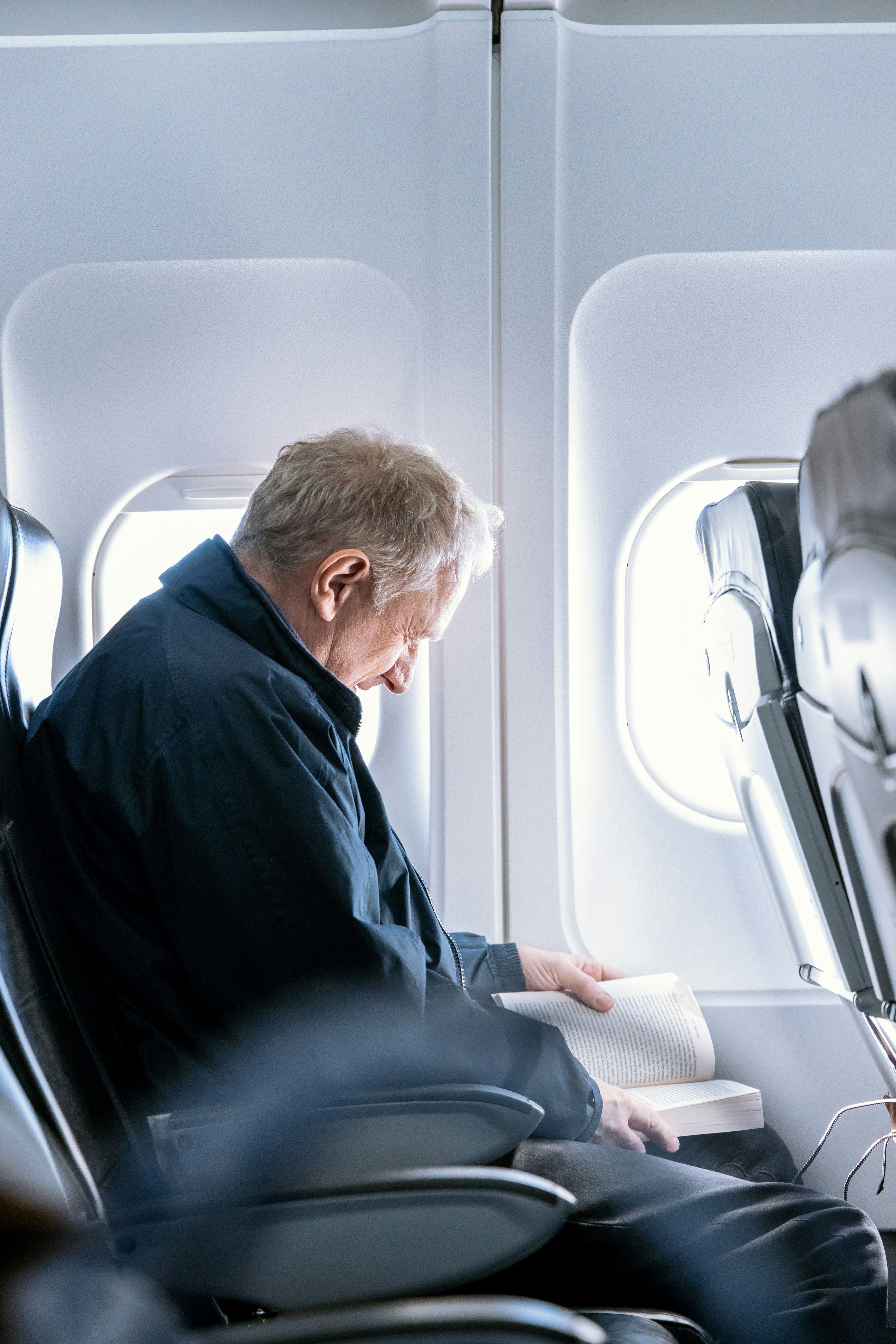 Un homme lisant un livre dans un avion | Source : Unsplash