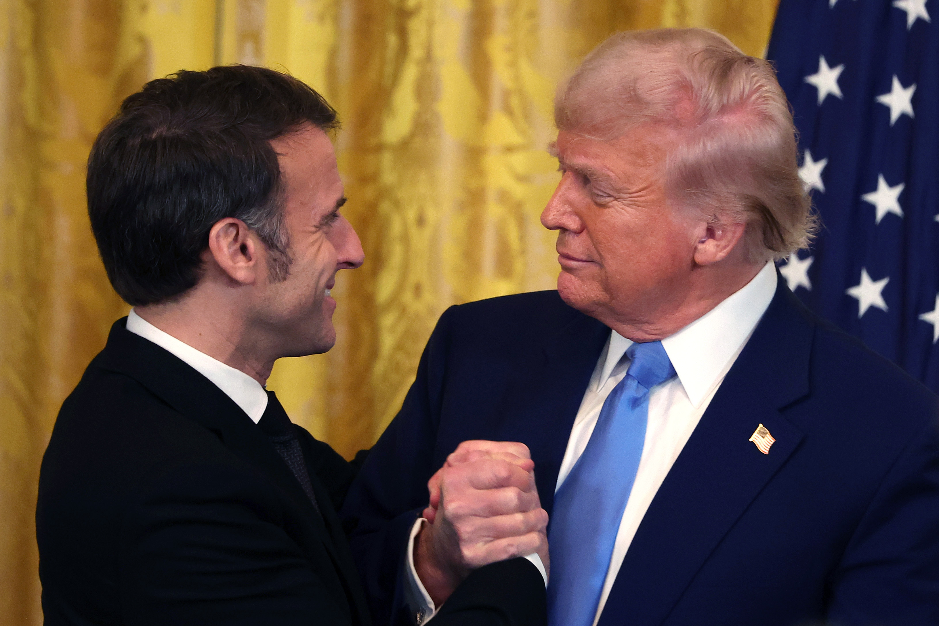 Emmanuel Macron et Donald Trump se serrant la main et s'embrassant dans la salle Est de la Maison Blanche à Washington, le 24 février 2025. | Source : Getty Images