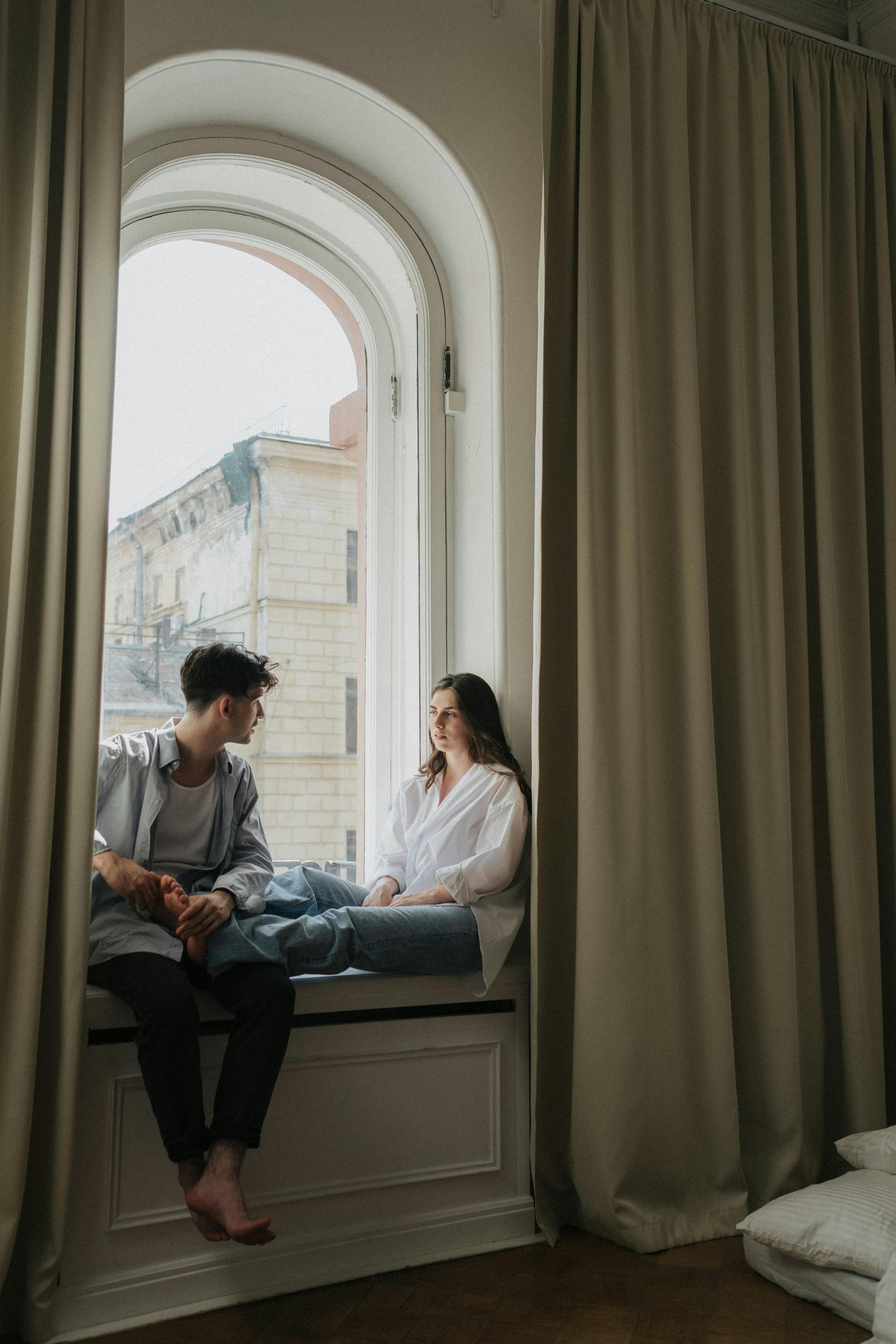 Un homme et une femme assis sur la fenêtre en train de parler | Source : Pexels