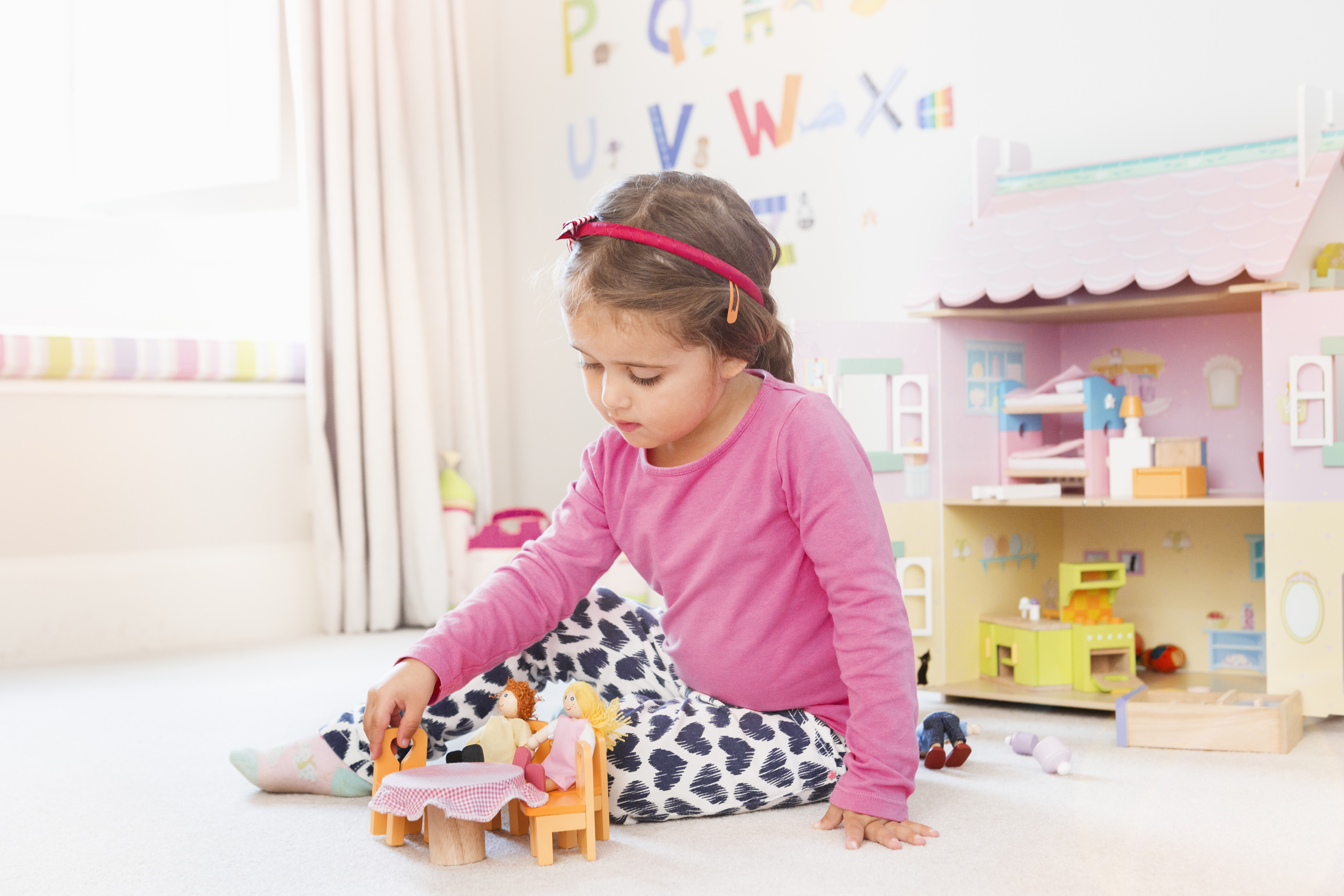 Jeune fille jouant avec une maison de poupées dans sa chambre | Source : Getty Images