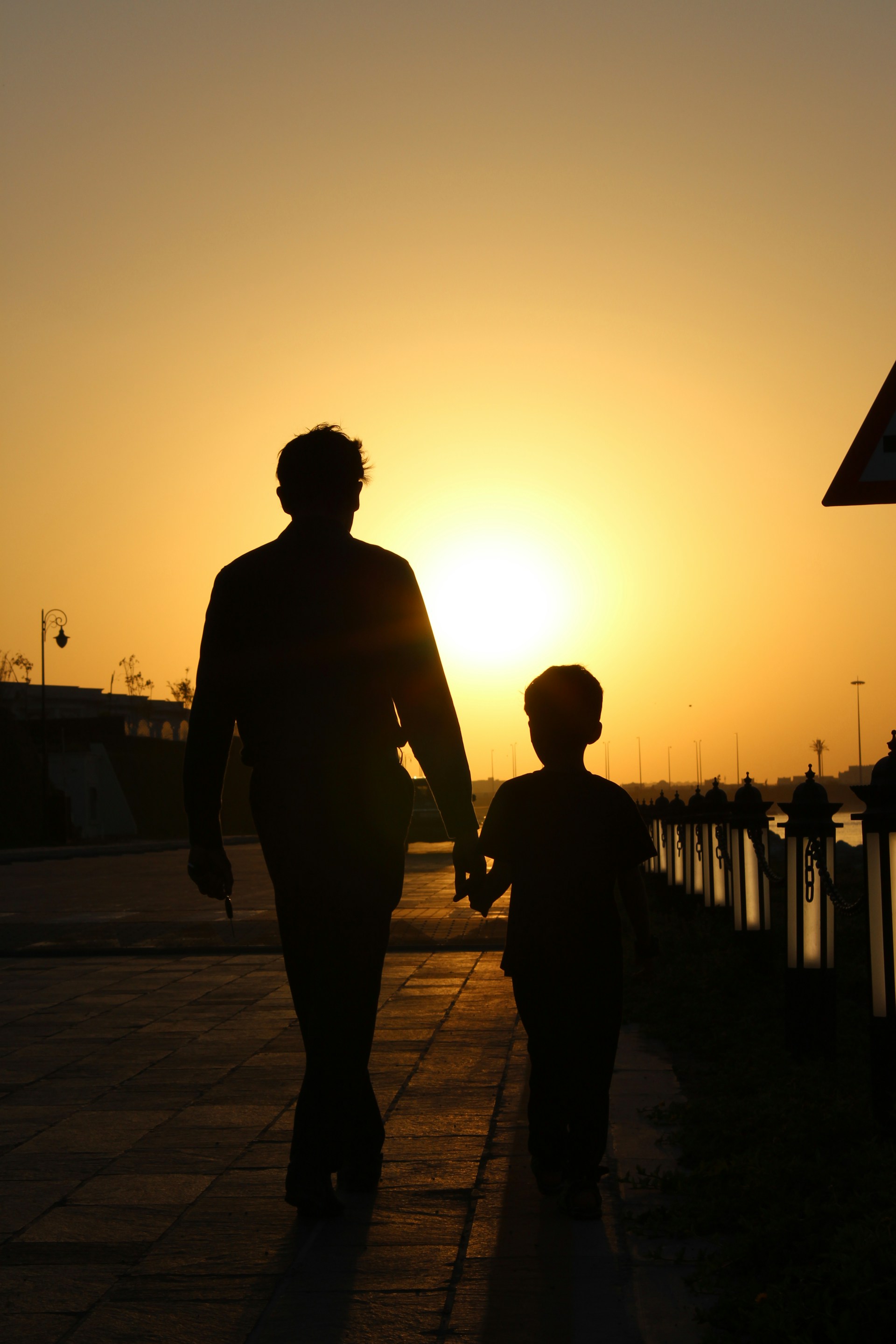 Silhouette d'un père et de son fils marchant dans la rue | Source : Unsplash
