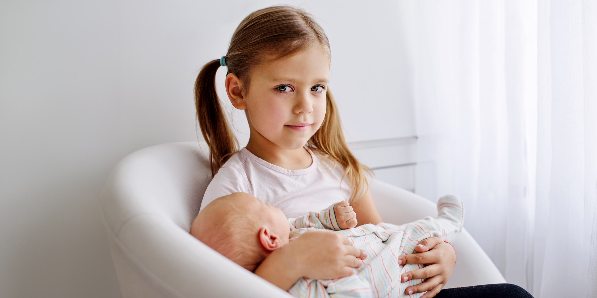 Une petite fille tenant un bébé | Source : Shutterstock