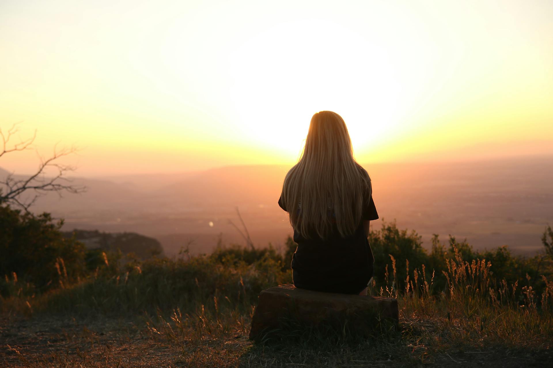 Une femme assise seule, regardant le coucher de soleil | Source : Pexels