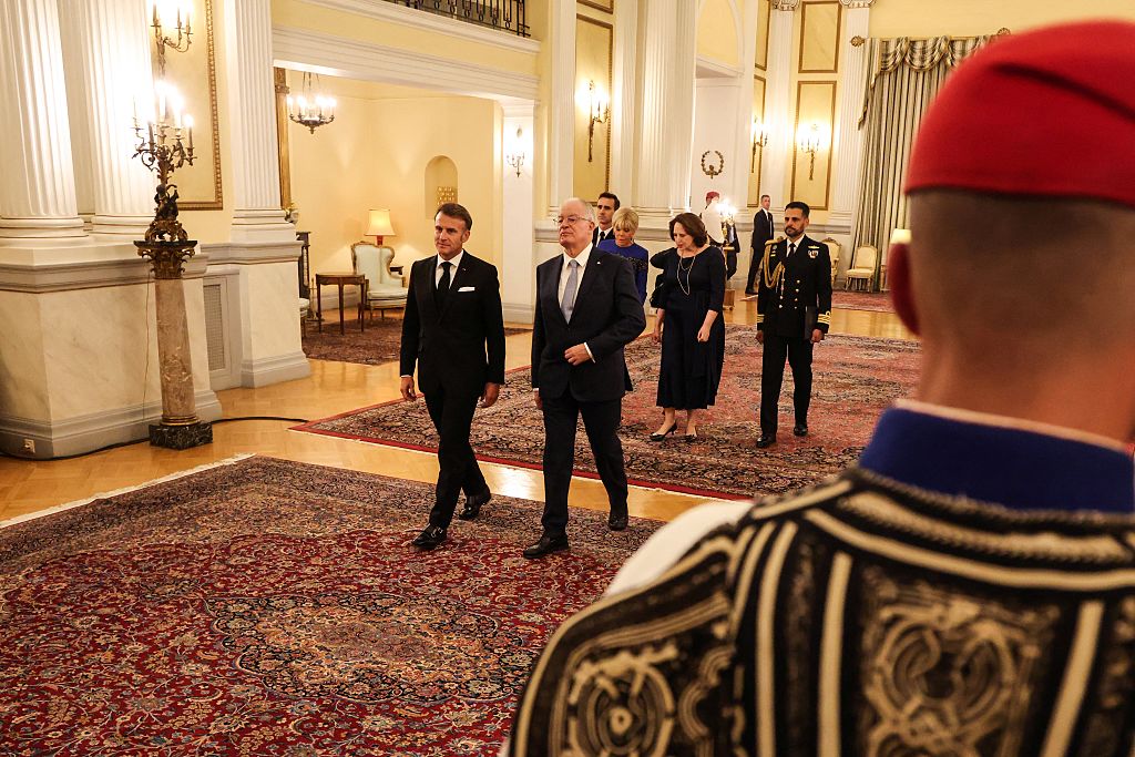 Le président français Emmanuel Macron (à gauche) et le président grec Konstantinos Tasoulas (à droite), suivis de l'épouse du président grec, Fani Stathopoulou (à l'arrière à droite), et de l'épouse du président français, Brigitte Macron (à l'arrière à gauche), arrivent pour un dîner officiel au palais présidentiel d'Athènes, le 24 avril 2026 I Source : Getty Images