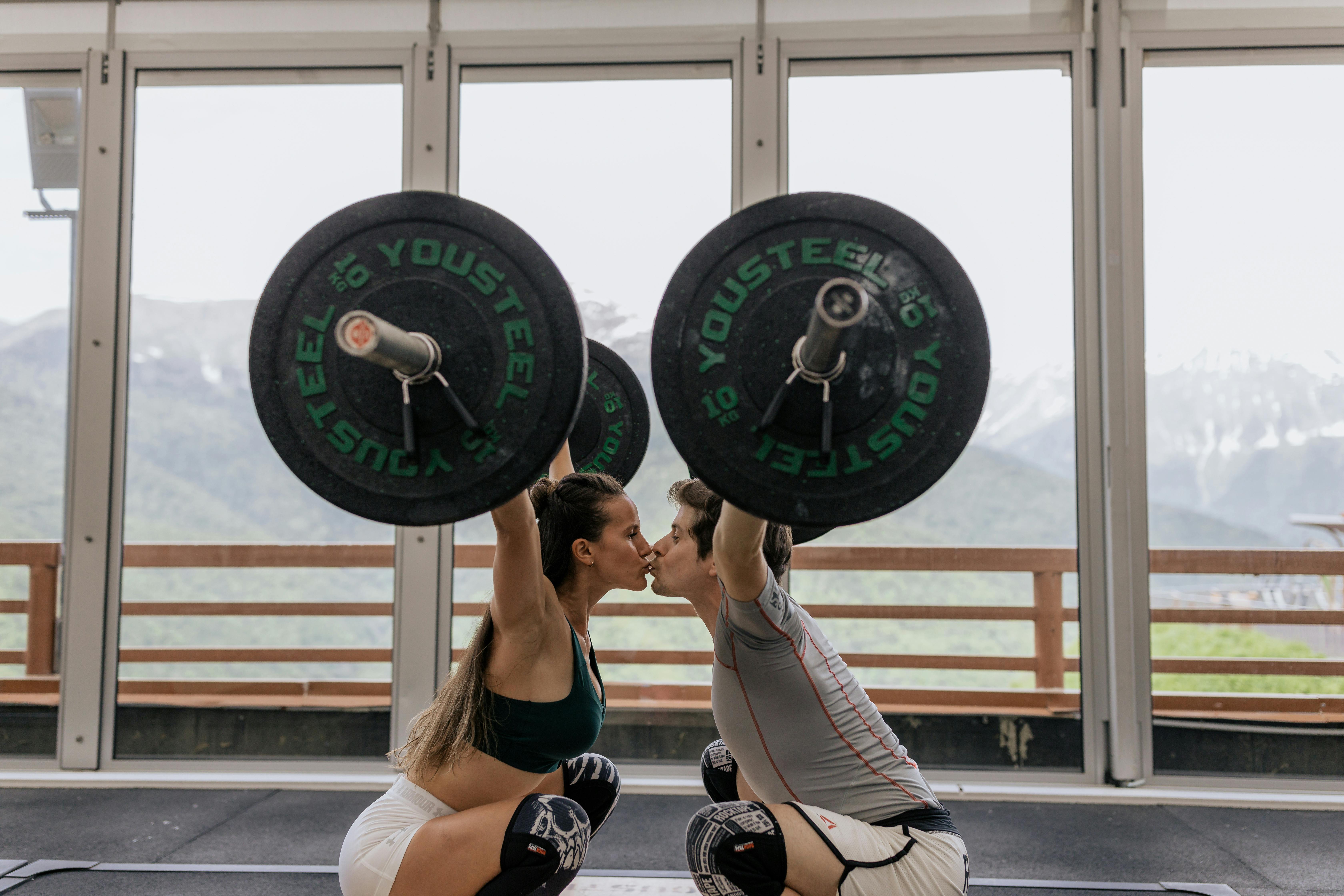 Un couple qui s'embrasse en soulevant des haltères | Source : Pexels