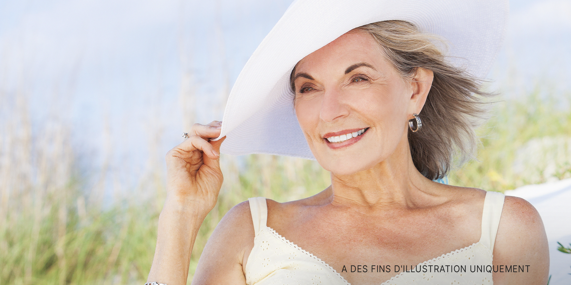 Une femme âgée vêtue de blanc et souriante | Source : Shutterstock