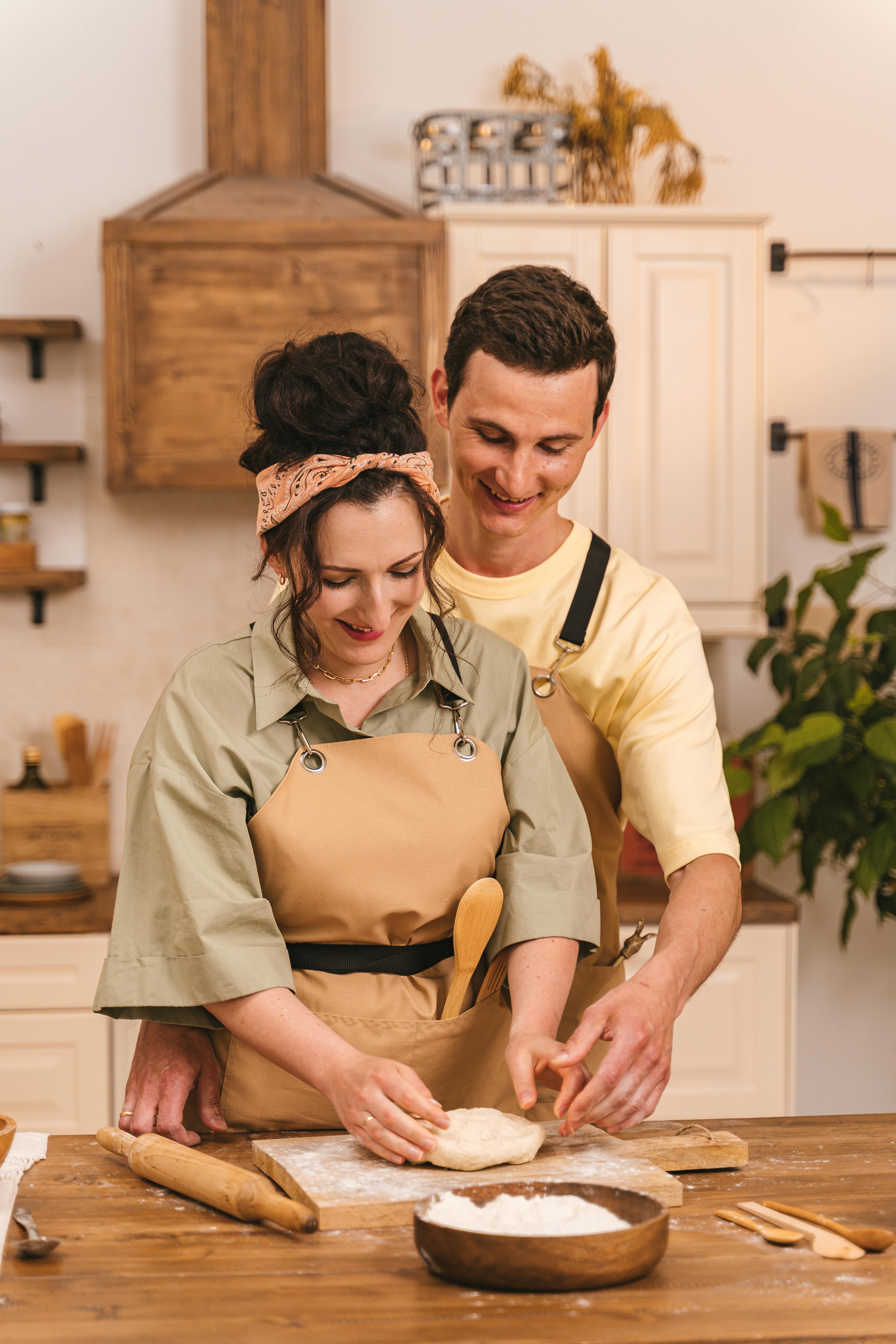 Un homme souriant regardant sa femme en train de cuisiner | Source : Pexels