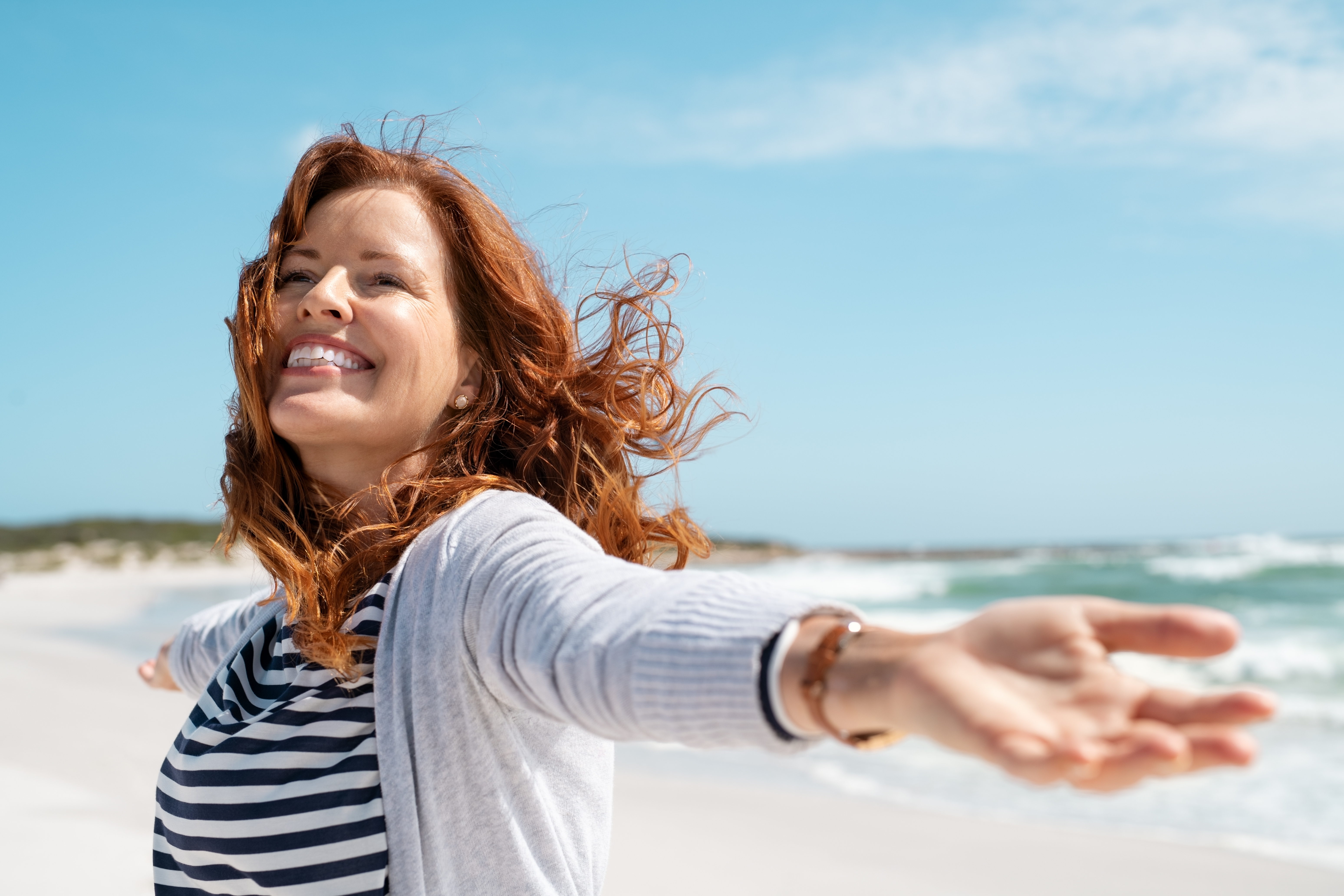 Une femme heureuse au bord de la mer | Source : Shutterstock