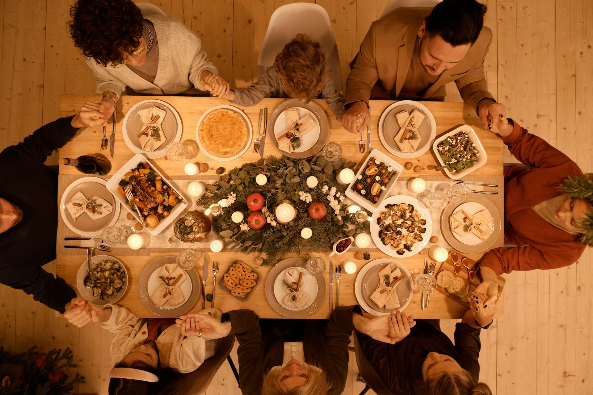 Vue de dessus d'une famille en train de prier avant le repas de Noël | Source : Pexels