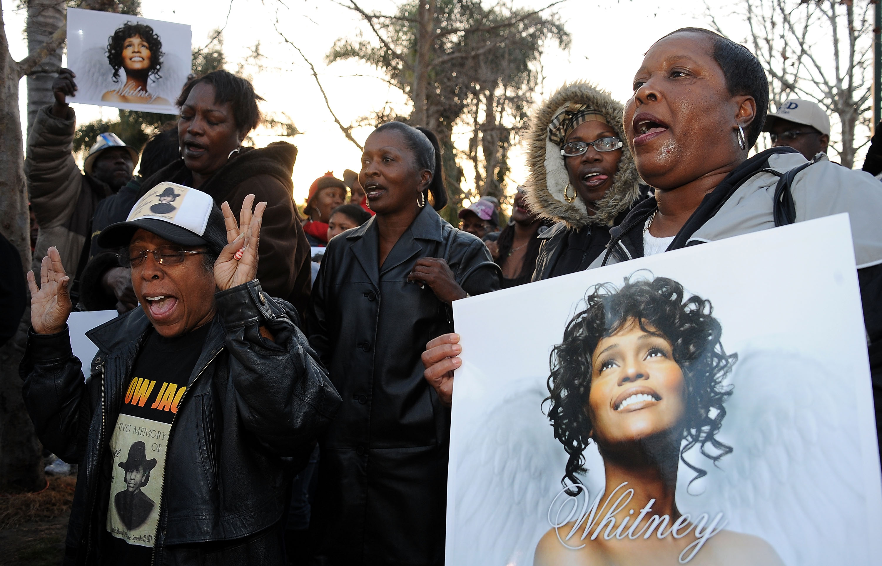 Des fans tenant des affiches de Whitney Houston lors de sa veillée à Leimert Park à Los Angeles, Californie, le 13 février 2012 | Source : Getty Images