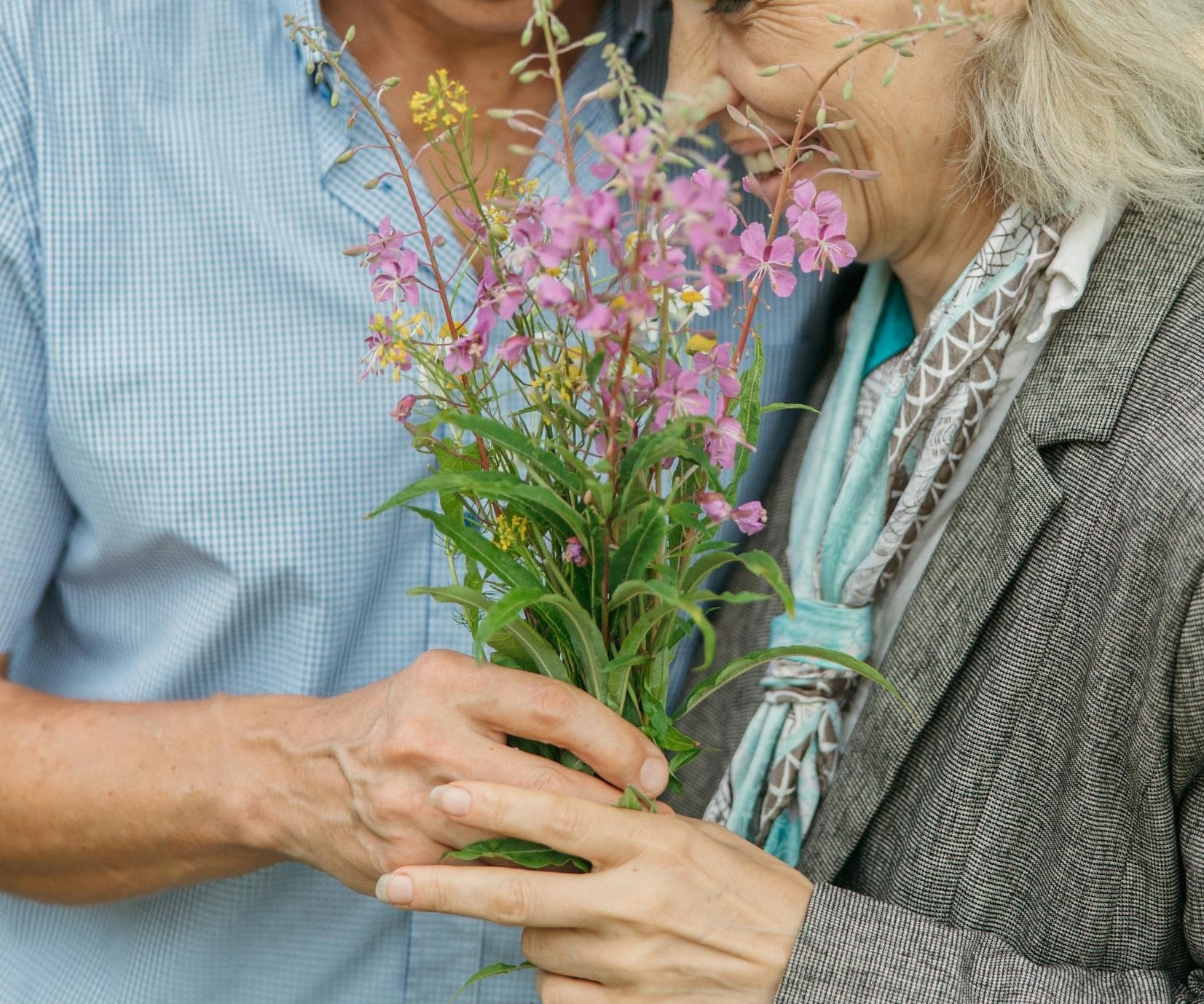 Gros plan d'un couple de seniors heureux tenant des fleurs | Source : Pexels