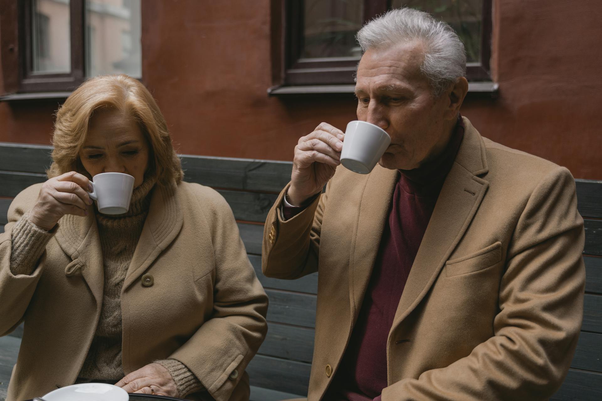 Un couple de seniors buvant un café assis sur un banc | Source : Pexels