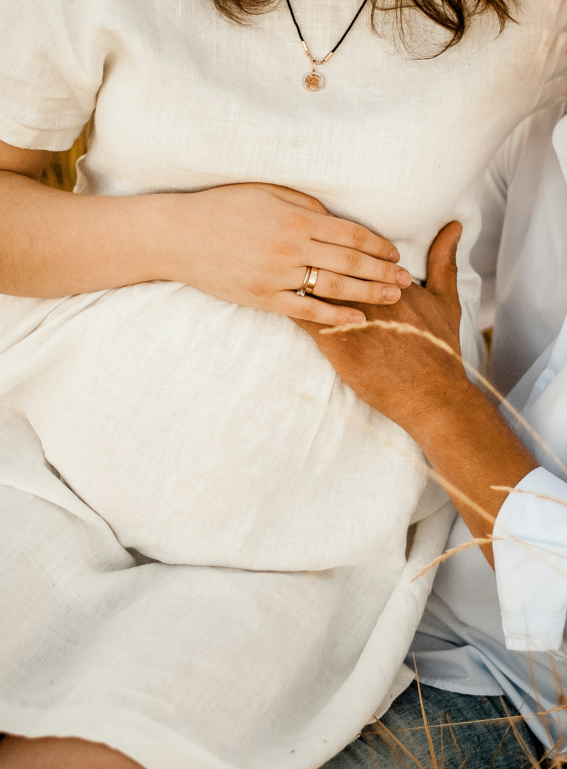 Une femme enceinte assise sur les genoux d'un homme qui touche doucement son ventre rond | Source : Unsplash