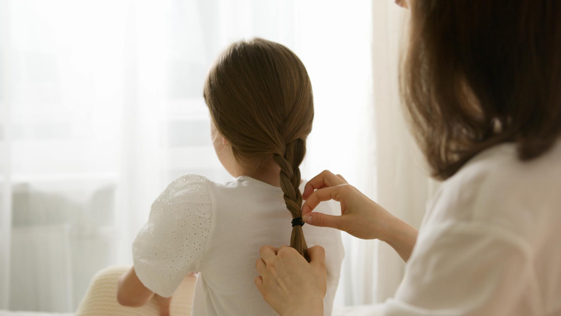 Une femme tresse les cheveux d'une petite fille | Source : Pexels