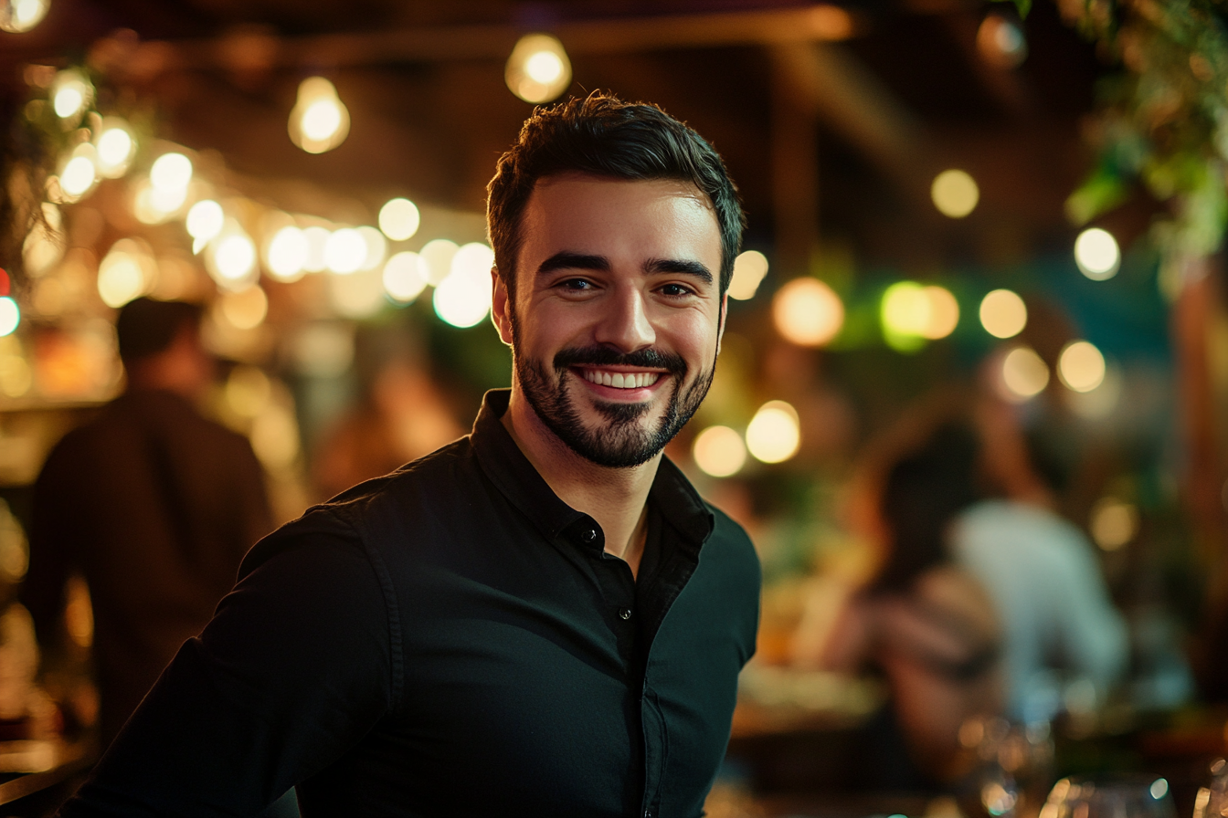 Un homme souriant chaleureusement, debout dans un beau restaurant | Source : Midjourney