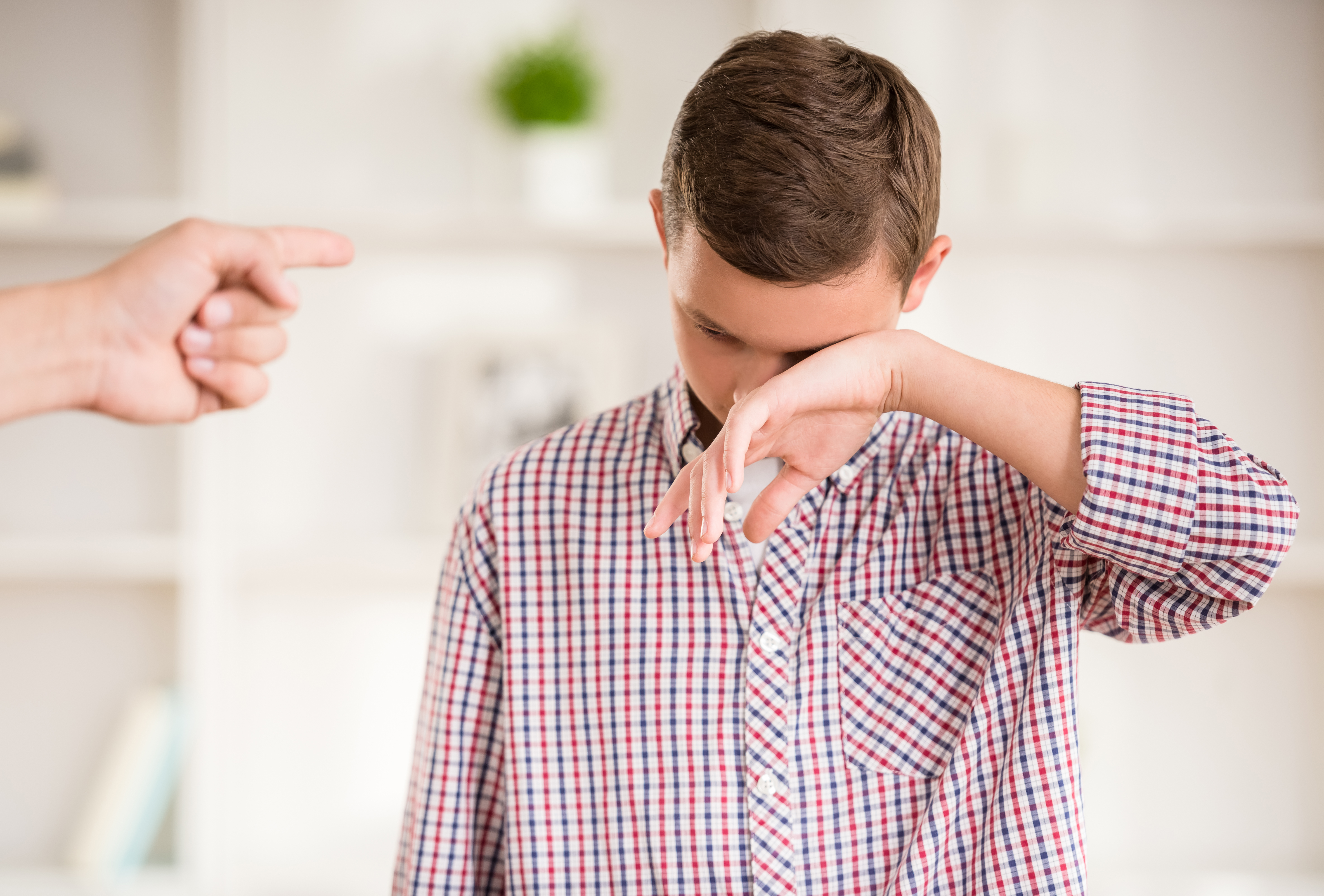 Un garçon semblant pleurer alors qu'un doigt est pointé sur lui | Source : Shutterstock