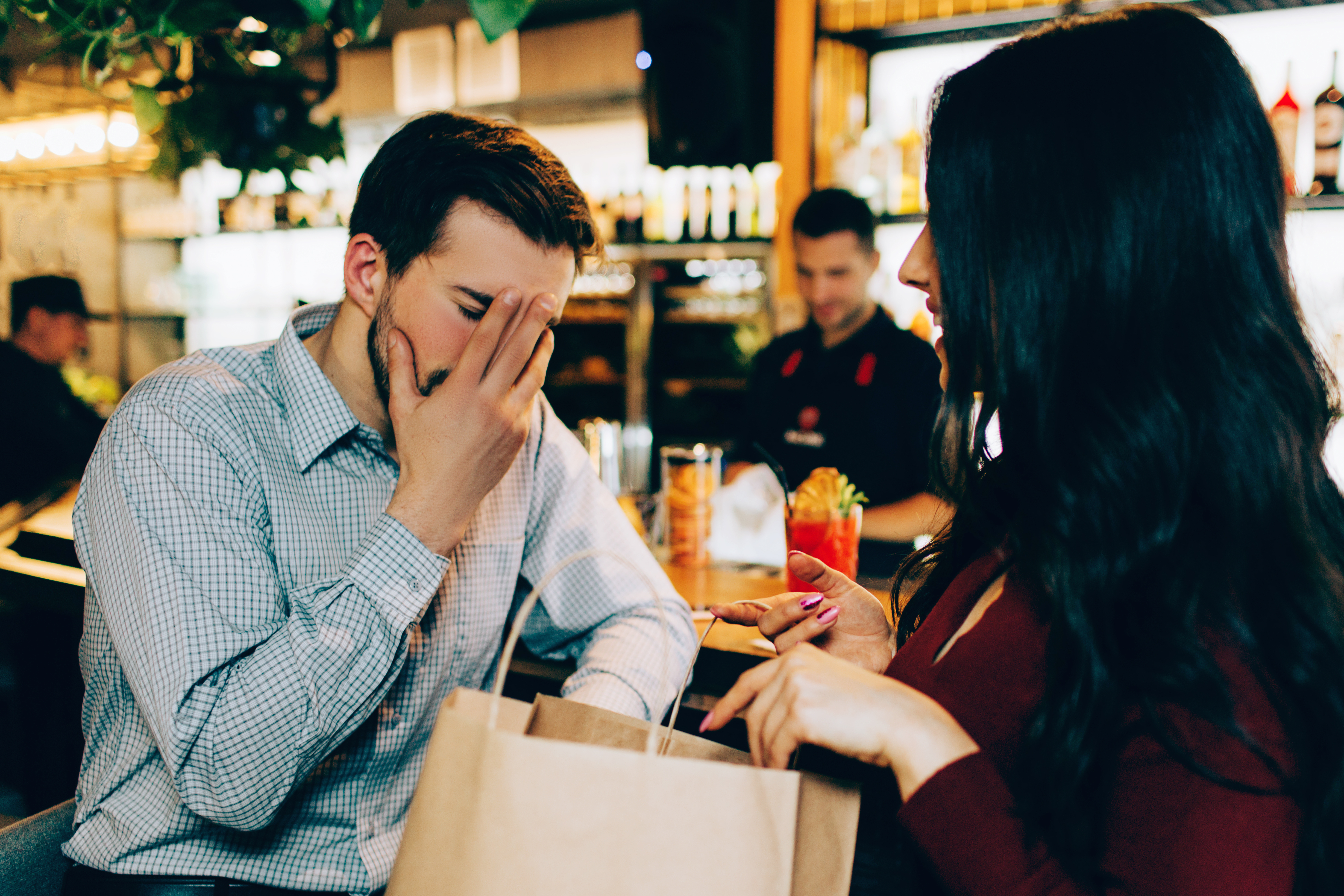 Un homme met sa main sur son visage pendant que la femme en face de lui continue de parler | Source : Shutterstock