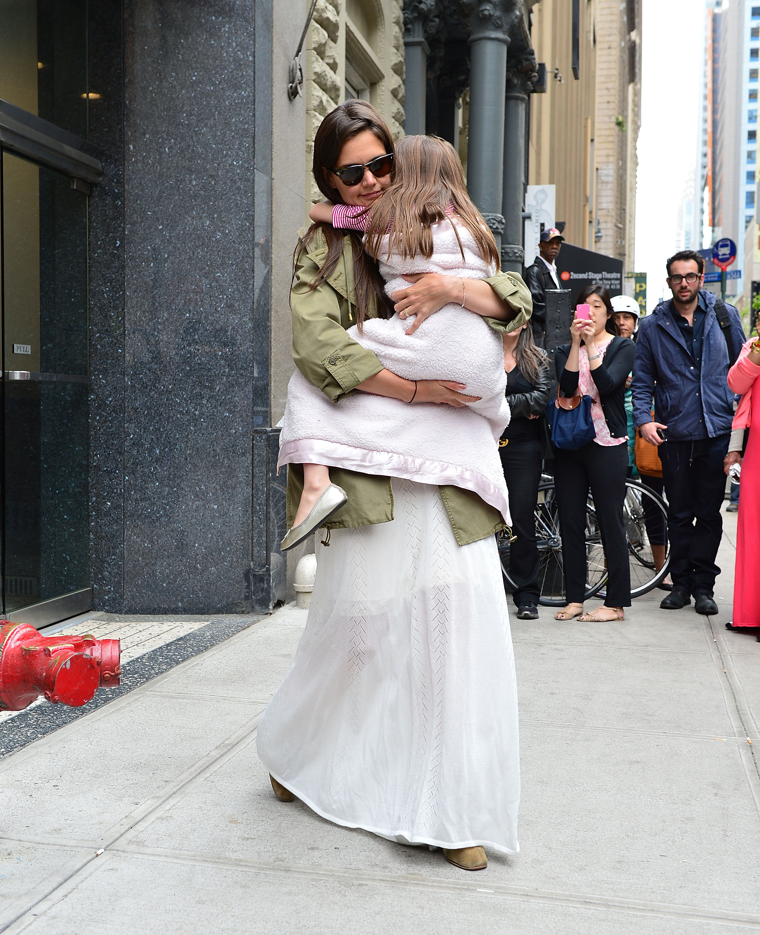 Katie Holmes serre sa fille Suri Cruise dans ses bras alors qu'elles se promènent dans Manhattan le 18 avril 2012 | Source : Getty Images