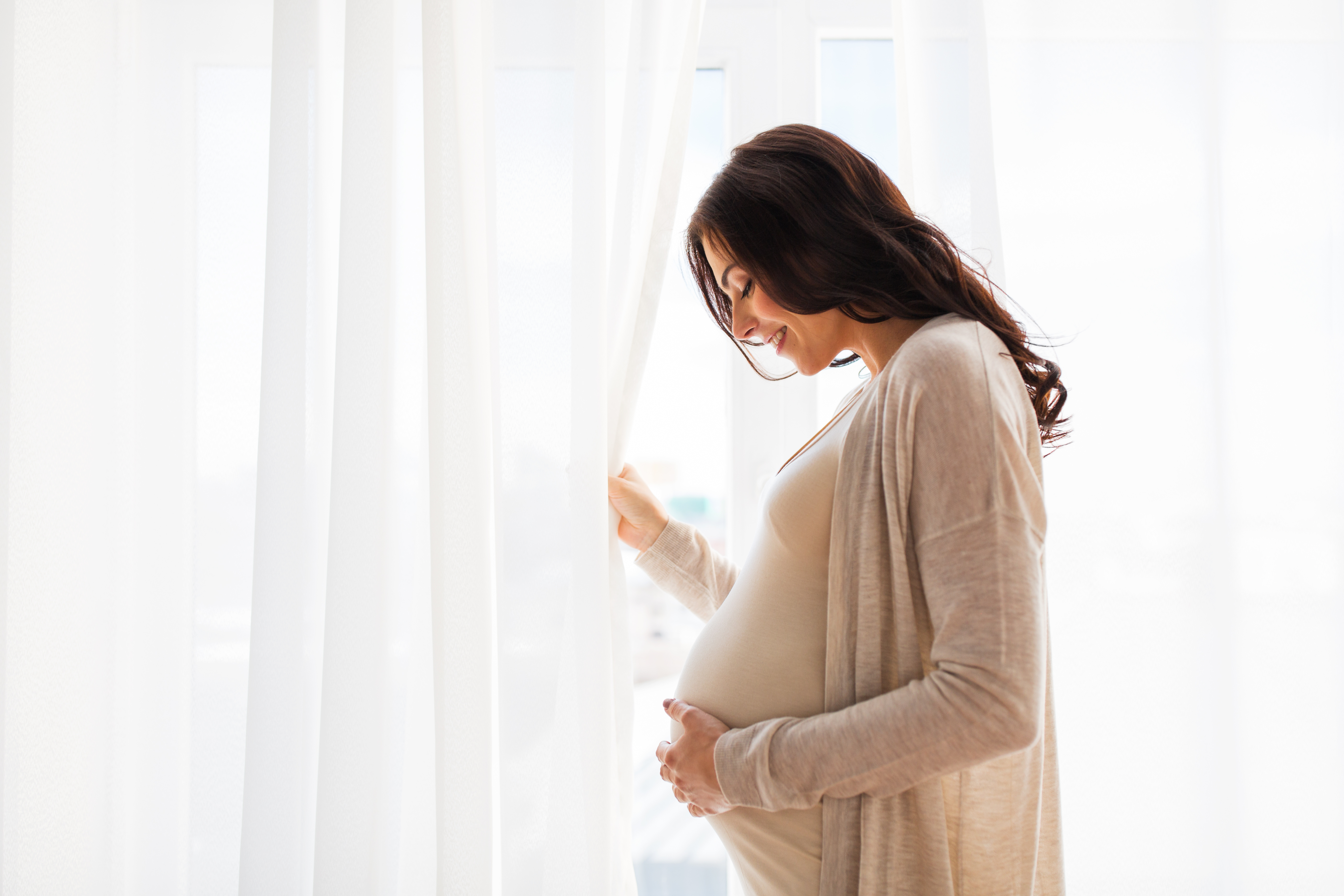 Une femme enceinte debout près d'une fenêtre | Source : Shutterstock