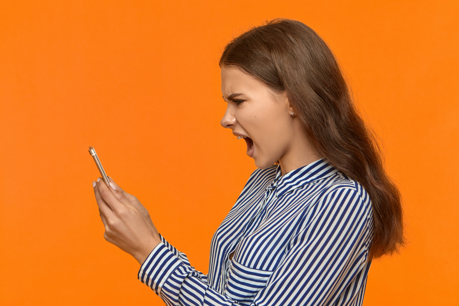 Une femme furieuse qui regarde son téléphone et crie | Source : Freepik
