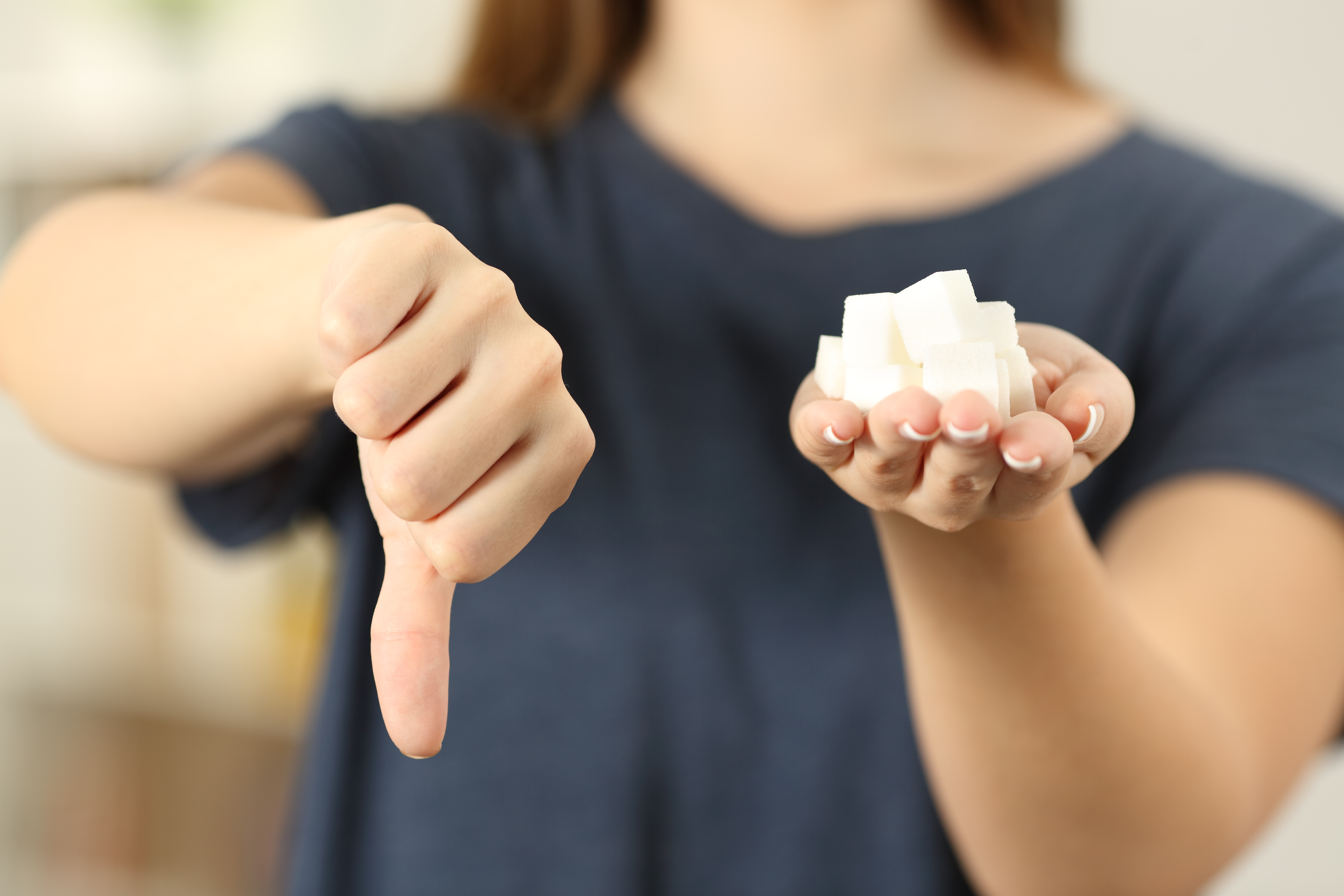 Une femme tenant des morceaux de sucre dans une main tout en leur donnant le pouce vers le bas avec l'autre | Source : Shutterstock