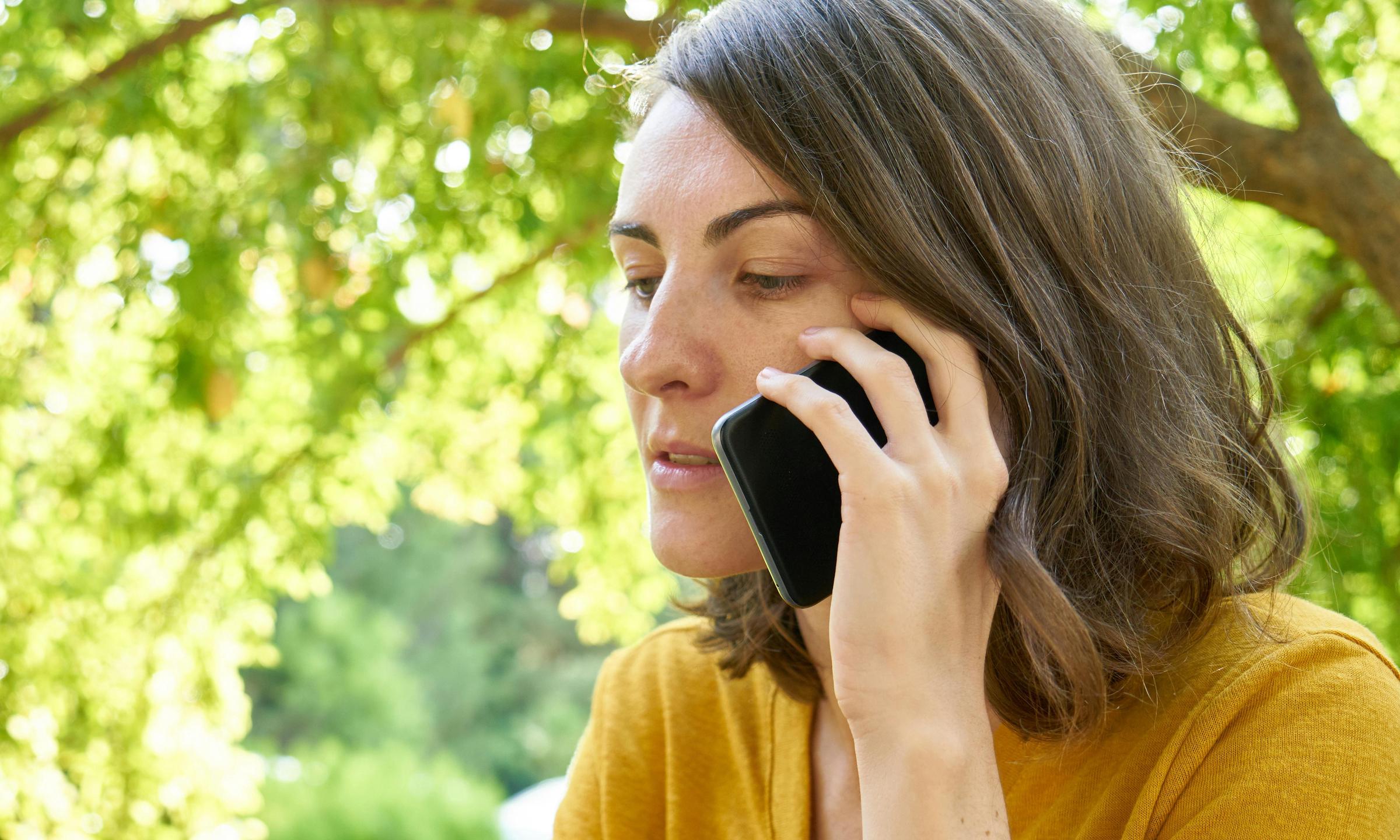 Une femme passant un appel sur un téléphone portable à l'extérieur | Source : Pexels