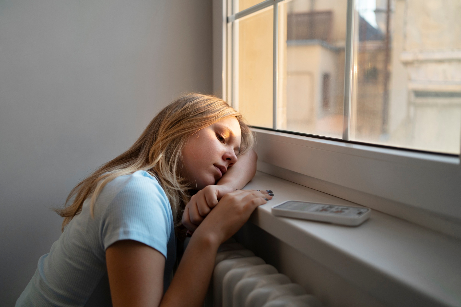 Une adolescente triste assise près de la fenêtre | Source : Freepik