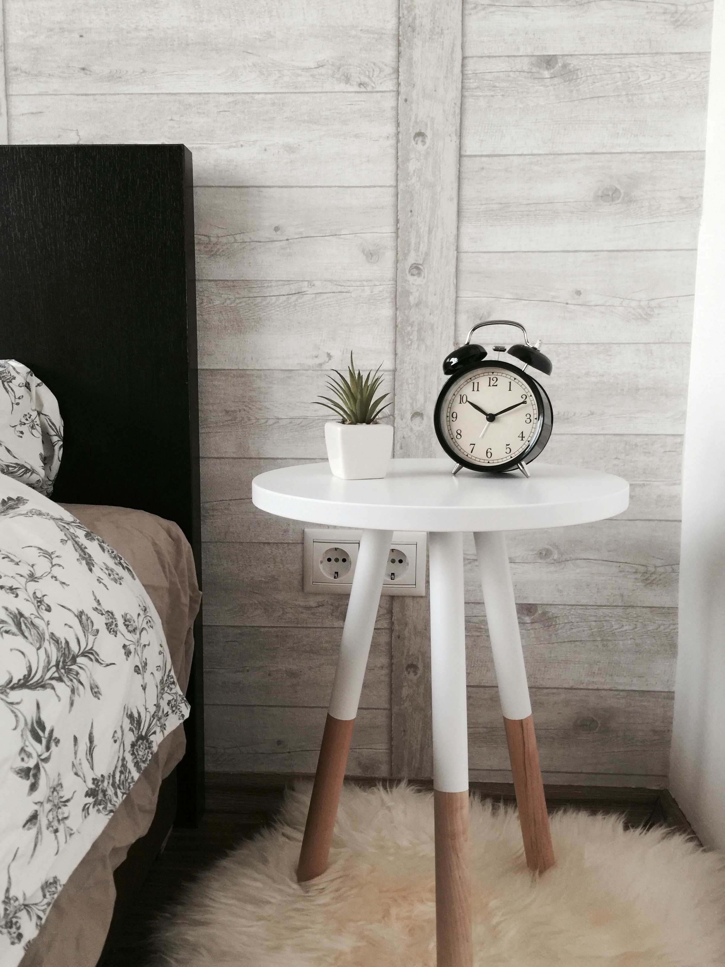 Un réveil posé sur une table en bois dans une chambre | Source : Unsplash