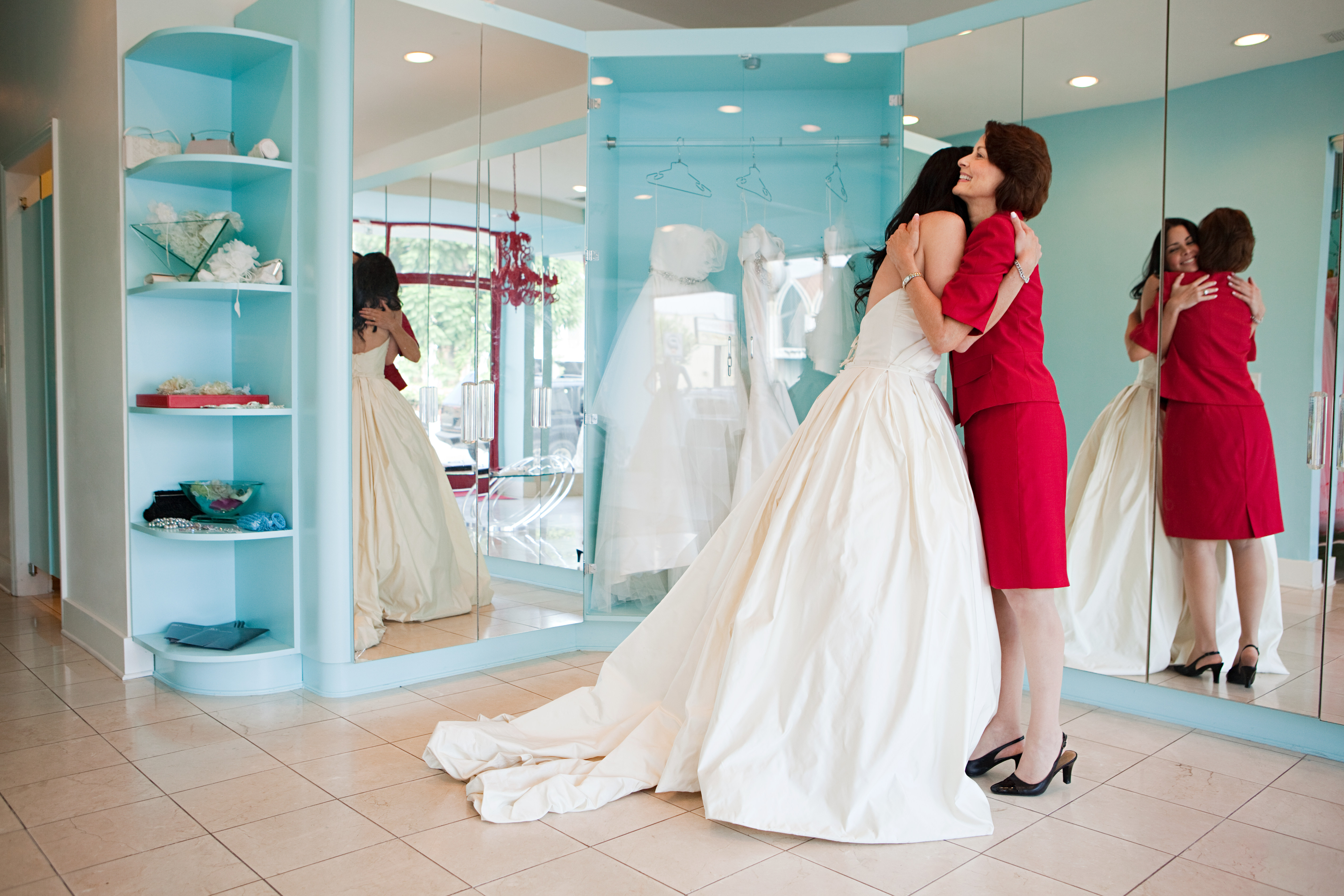 Fille essayant sa robe de mariée, embrassant sa mère | Source : Getty Images