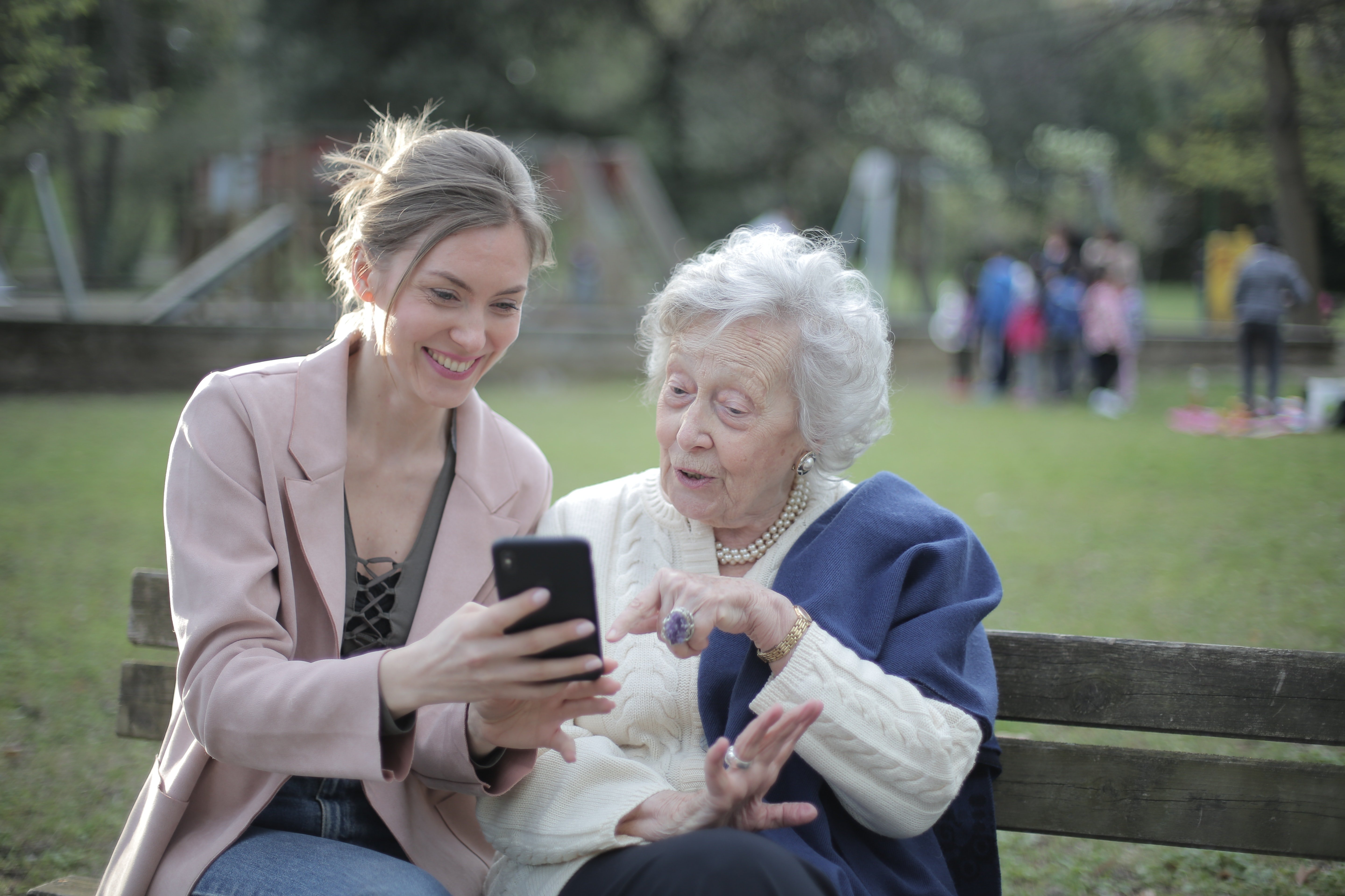 Une femme âgée assise avec une jeune femme tenant un téléphone dans sa main. | Photo : Pexels