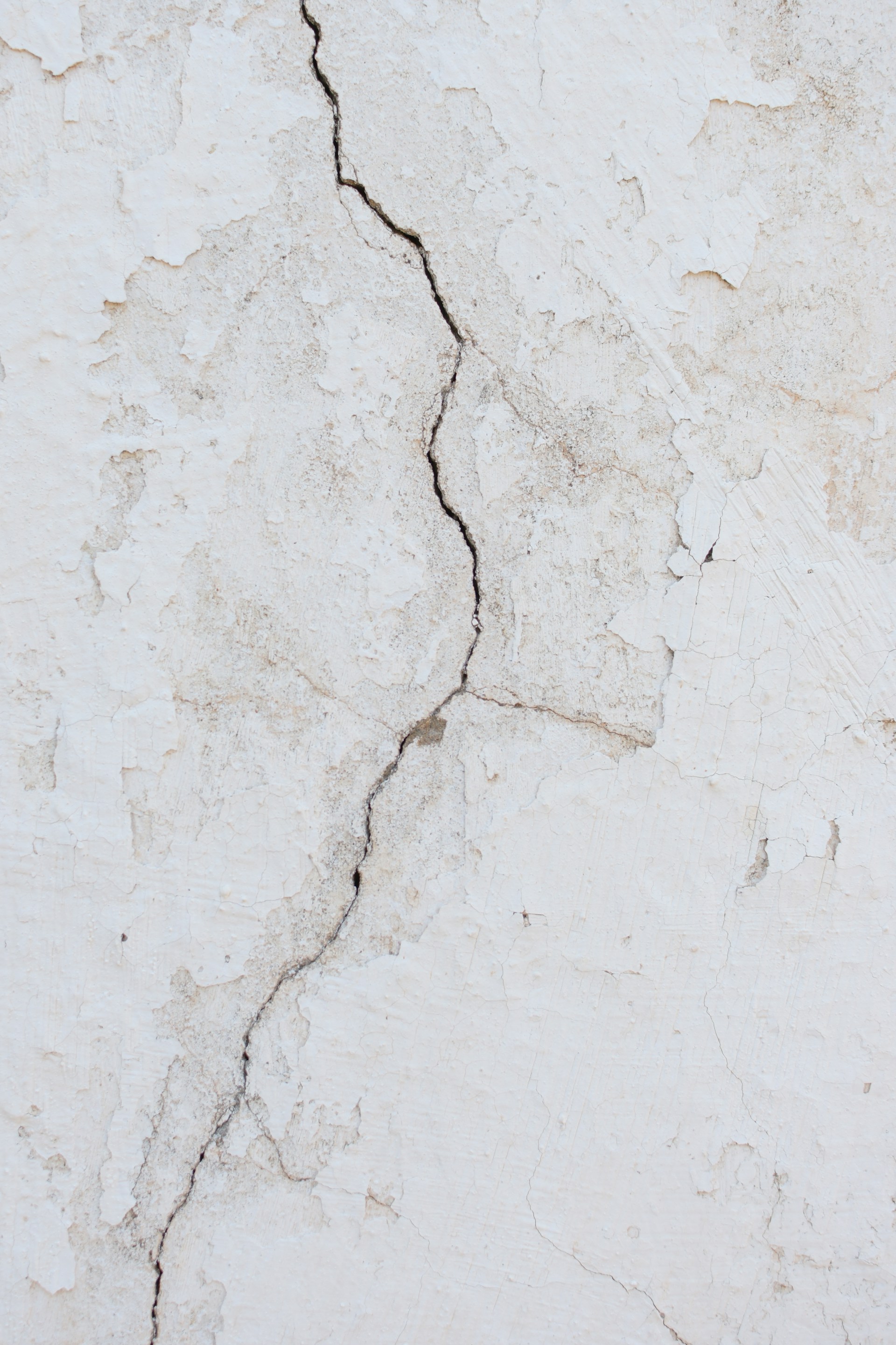Fissures sur un vieux mur blanc | Source : Unsplash