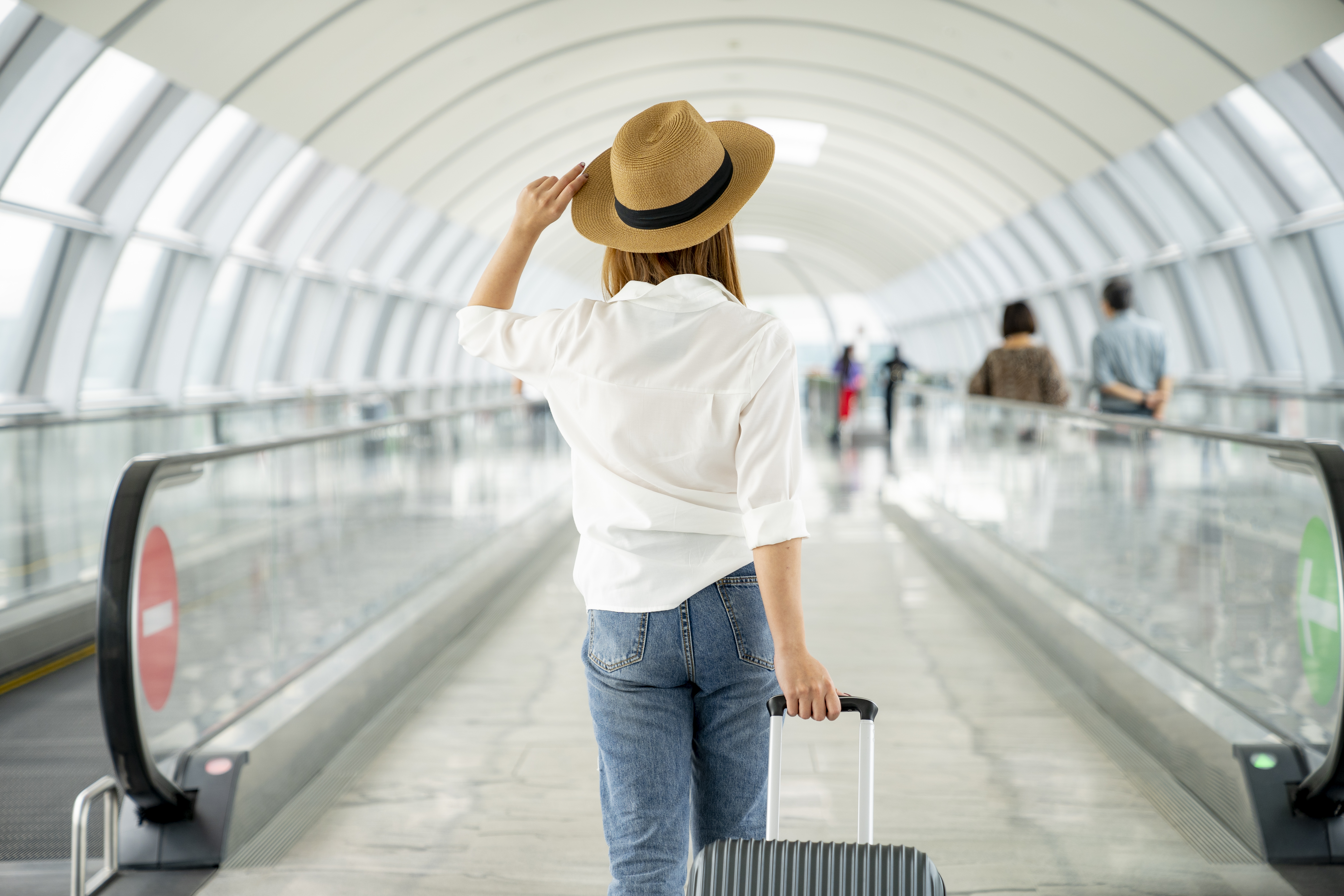 Jeune voyageuse décontractée avec une valise à l'aéroport | Source : Getty Images