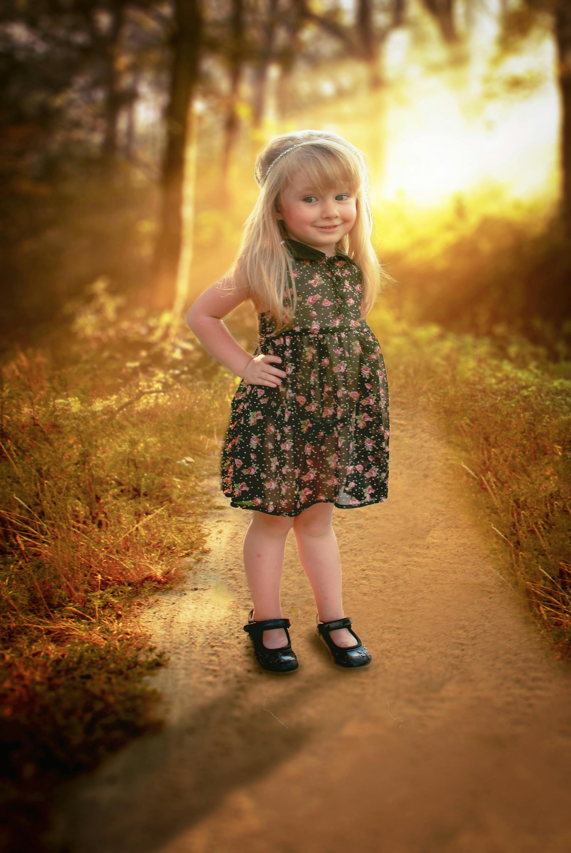 Une petite fille heureuse, vêtue d'une robe à fleurs, debout sur un sentier | Source : Pexels