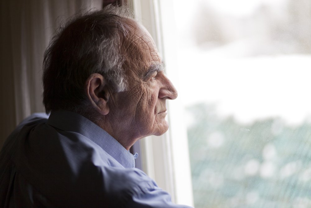 Un homme âgé pensif devant la fenêtre. | Photo : Shutterstock