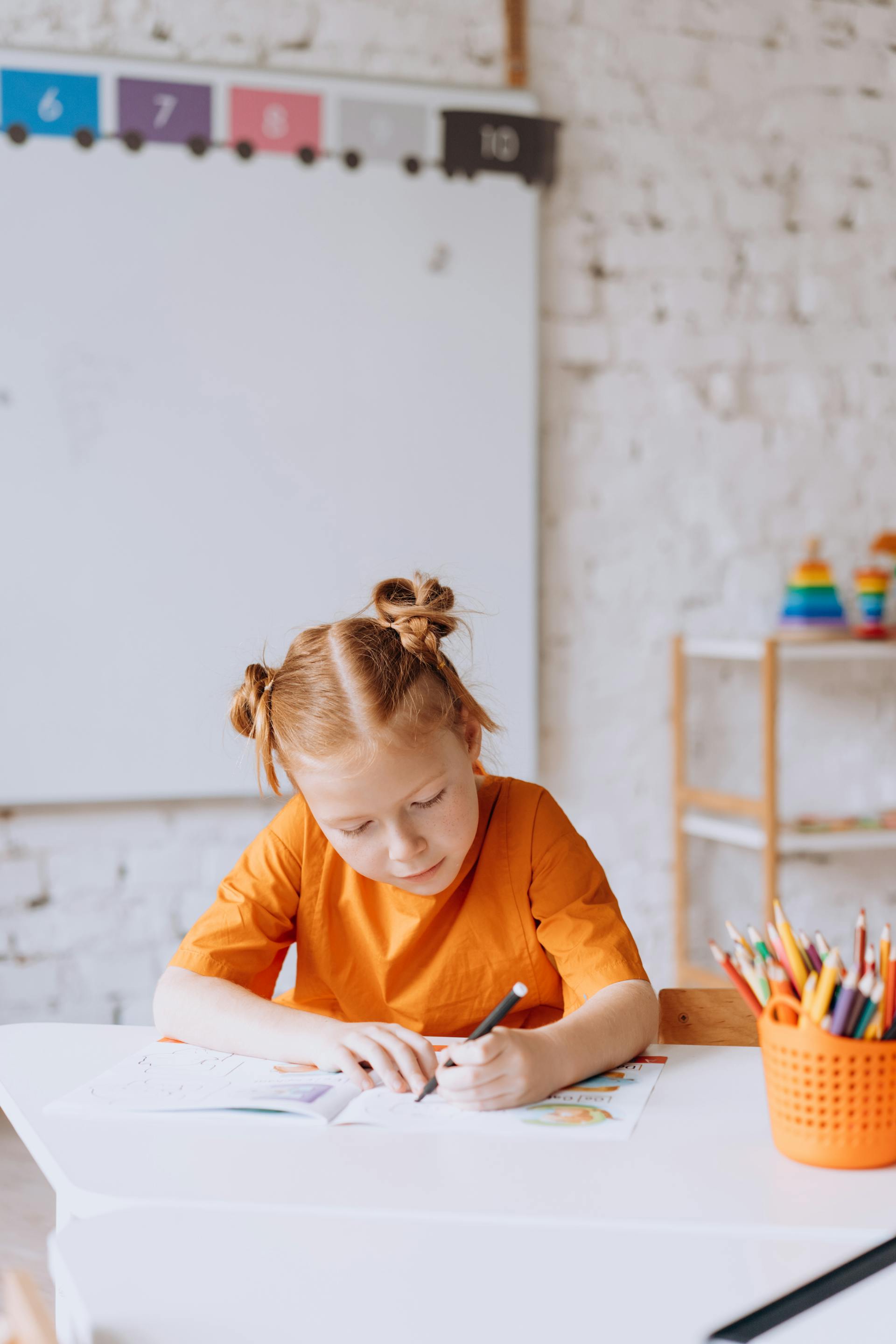 Une petite fille en train de colorier sur un livre | Source : Pexels