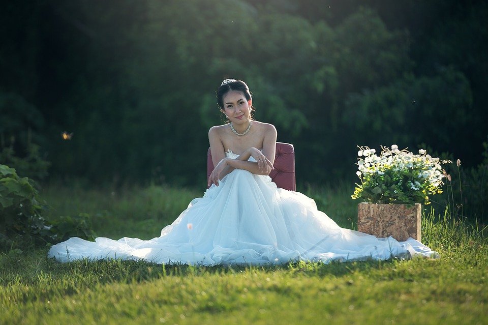 Une femme qui s'assit dans une jardin vêtue d'une robe de mariage | Photo : Pixabay