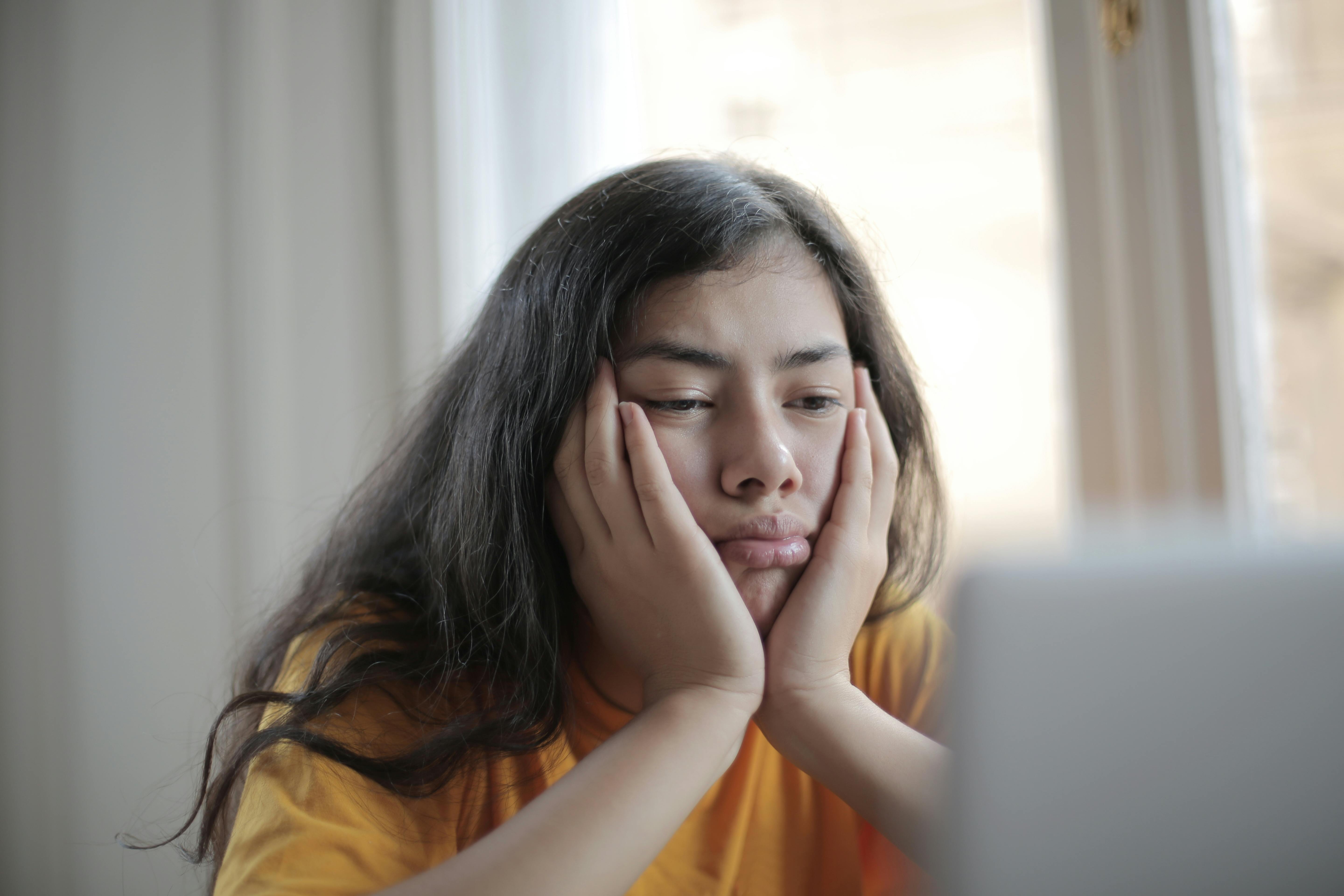 Une fille malheureuse assise et regardant un écran | Source : Pexels