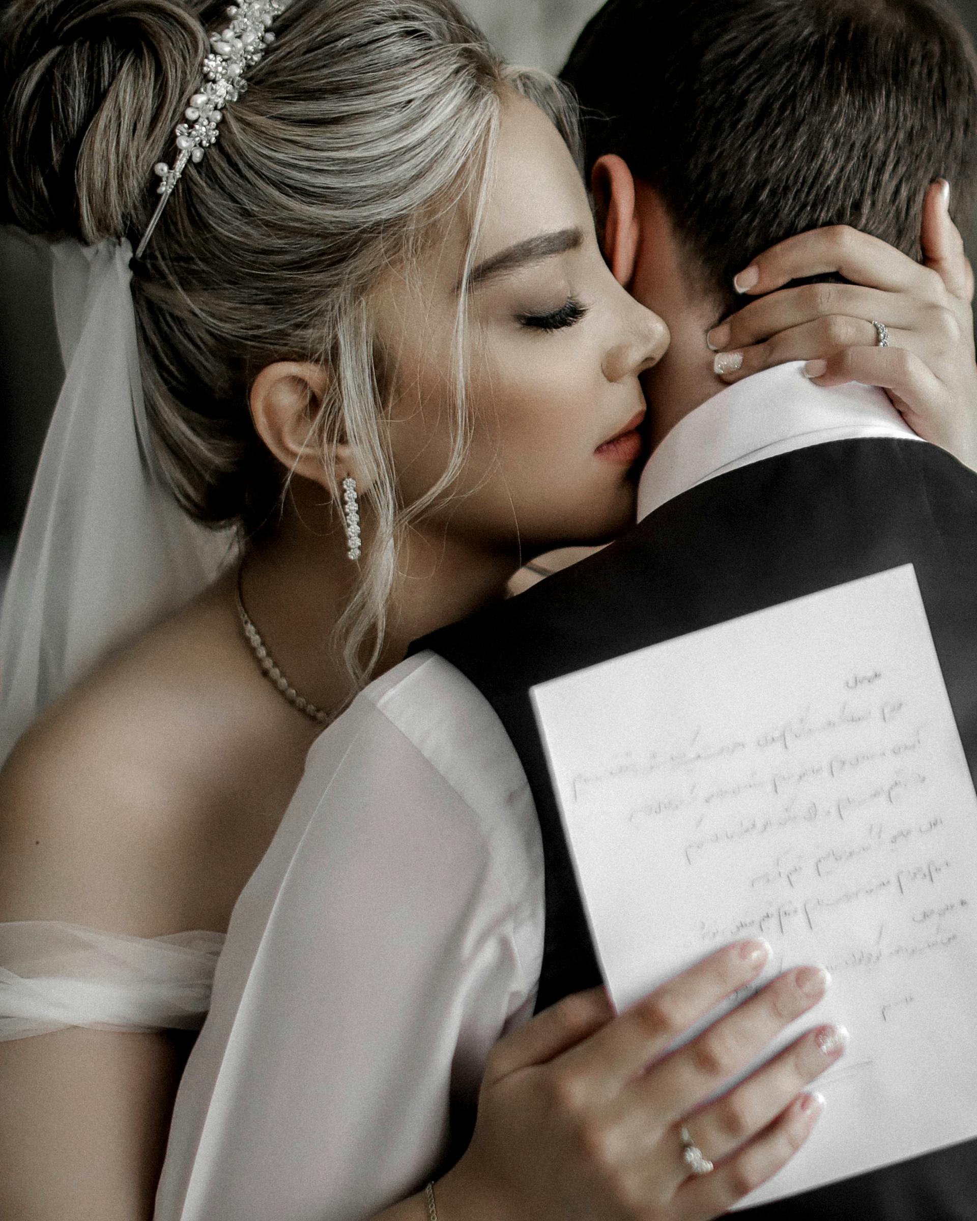 Une mariée étreint un marié tout en tenant un morceau de papier | Source : Pexels